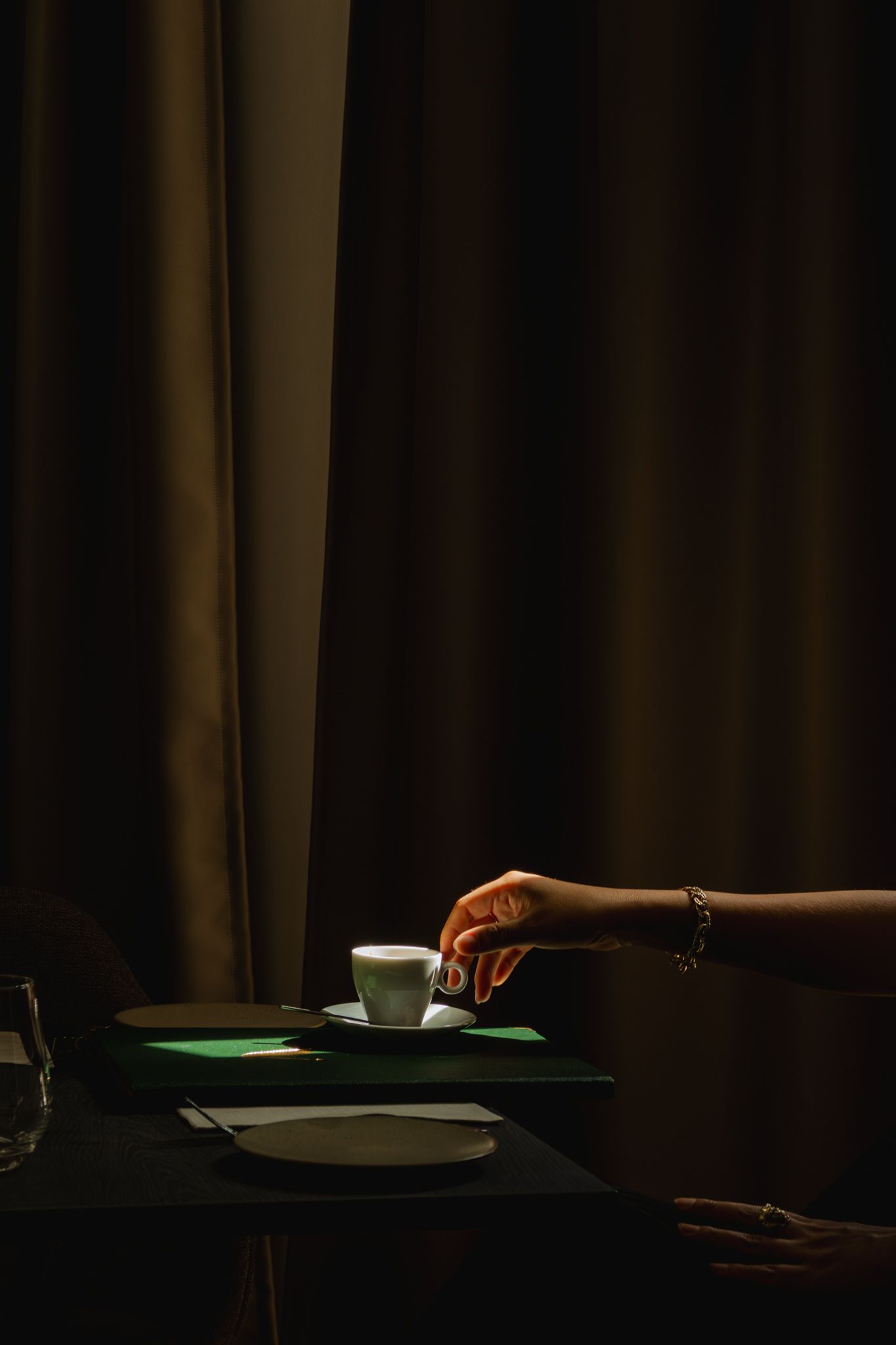 A sequence of dark images showing hands placing plates and utensils on a dining table in dim lighting.