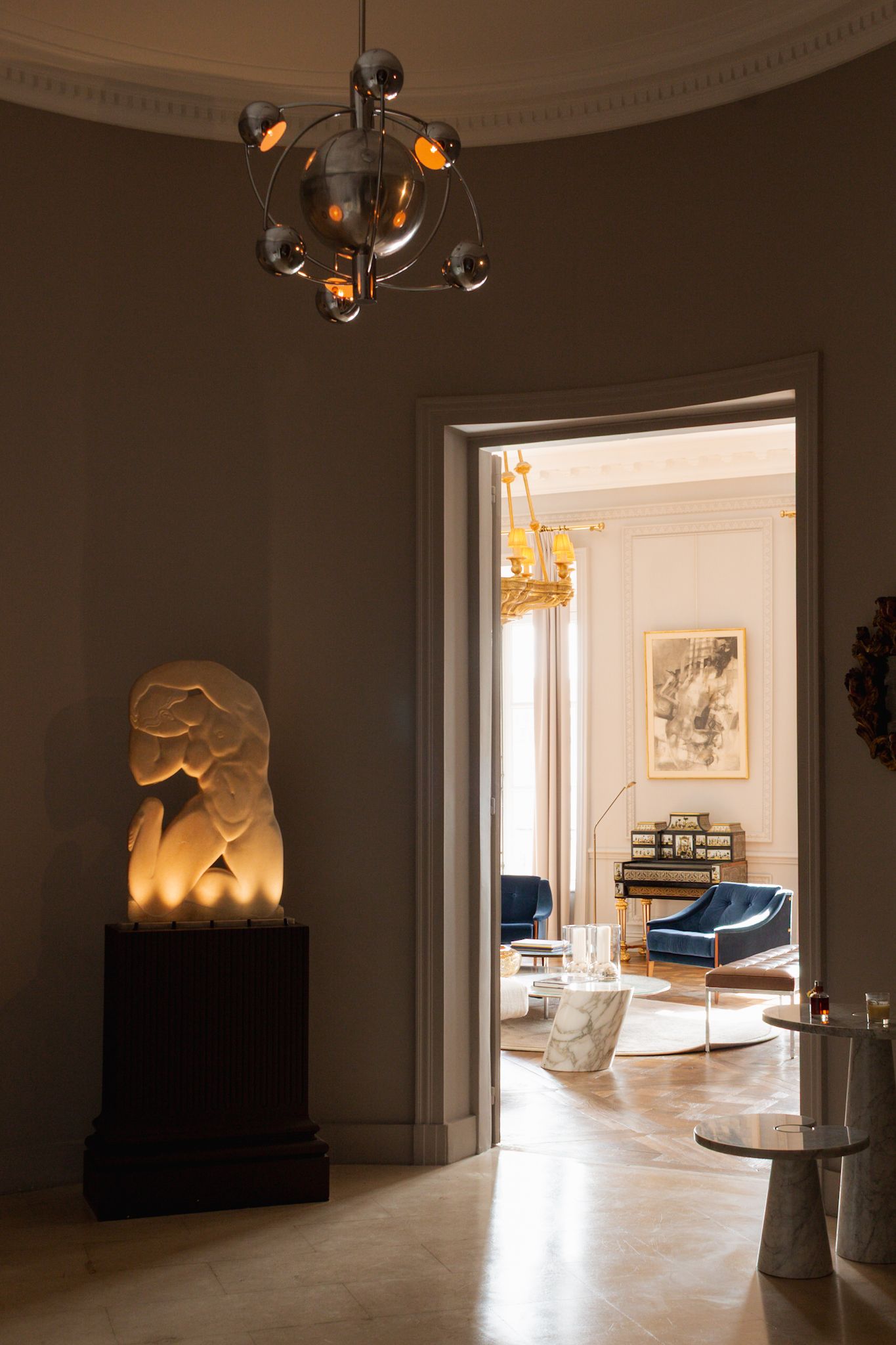 Minimalist interior room with moody lighting, white walls, and doorways leading to adjacent spaces.