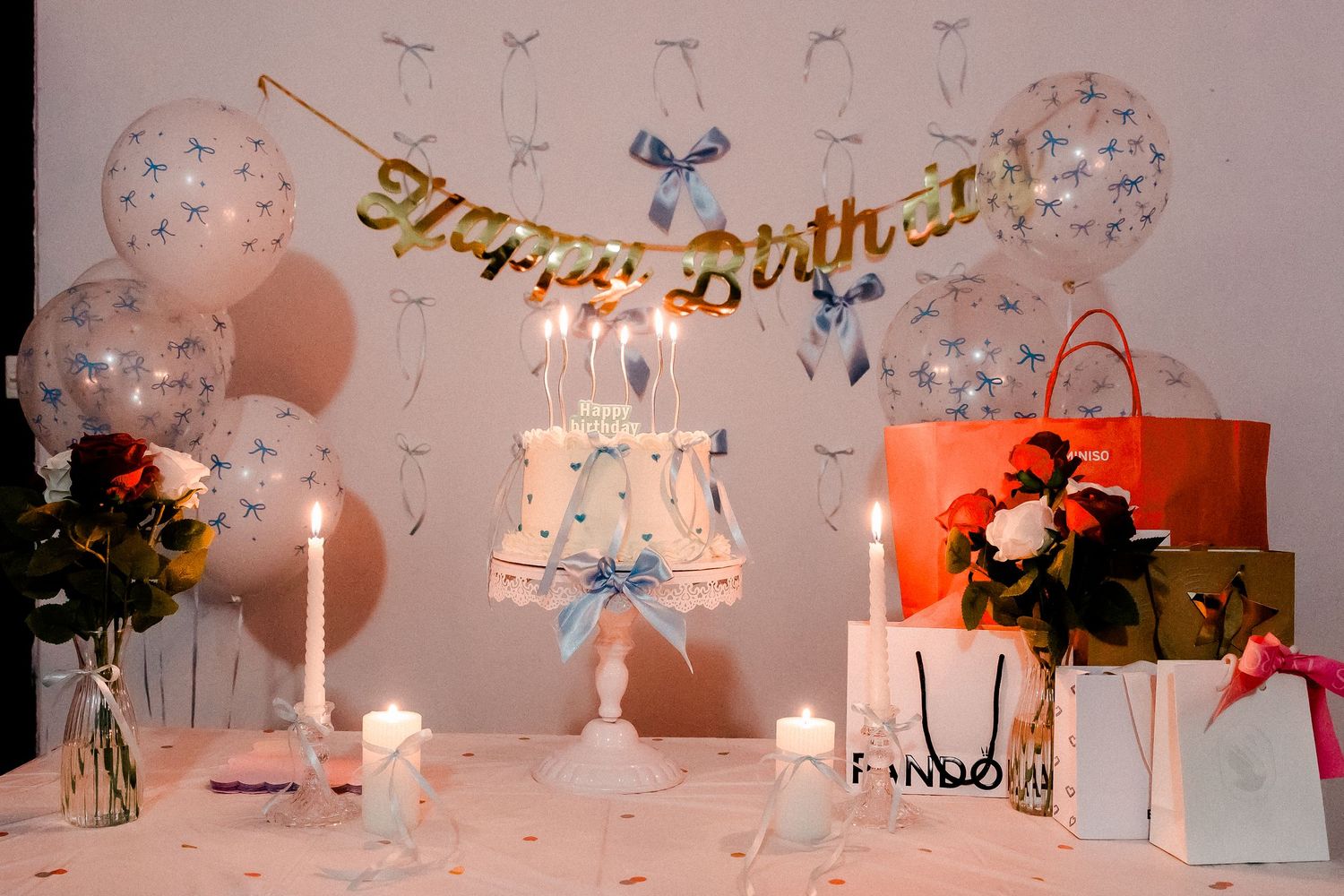 Elegant birthday party decor with transparent balloons, candles and a Happy Birthday banner.