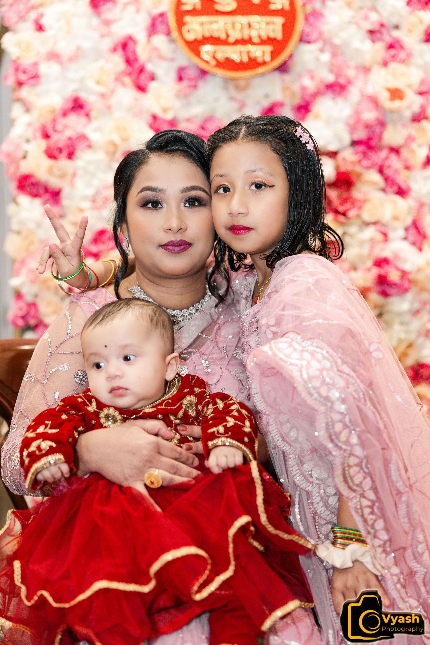 Family gathering in traditional attire against floral backdrop.