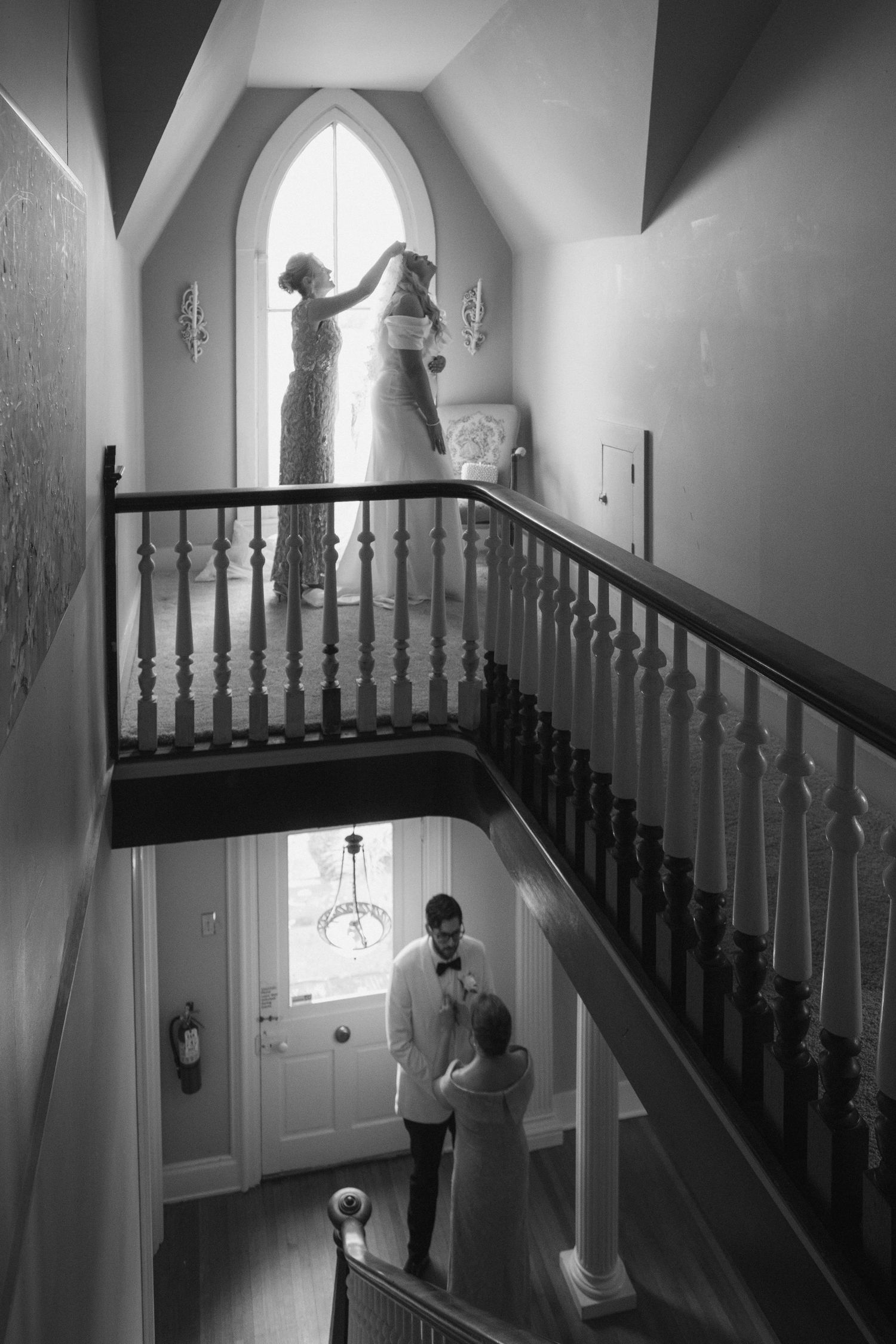 A black and white photo series showing figures ascending a staircase with wooden railings and arched windows.