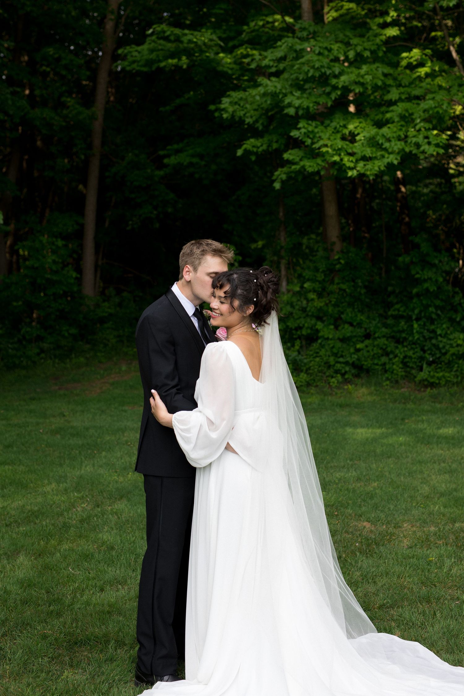 A romantic wedding couple shares intimate moments in a lush green garden setting.