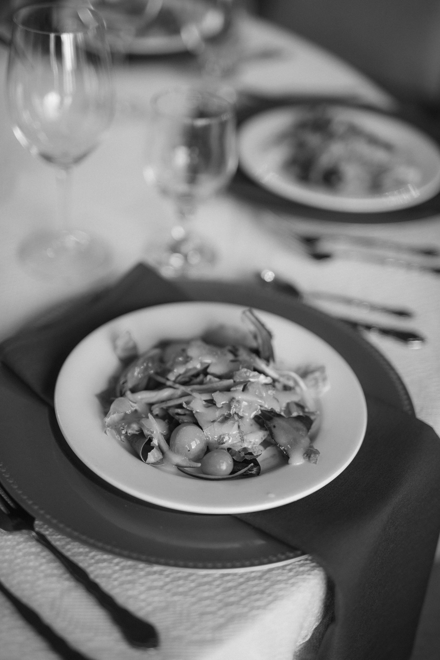 Black and white photograph of elegant plated dishes on a formal dining table.