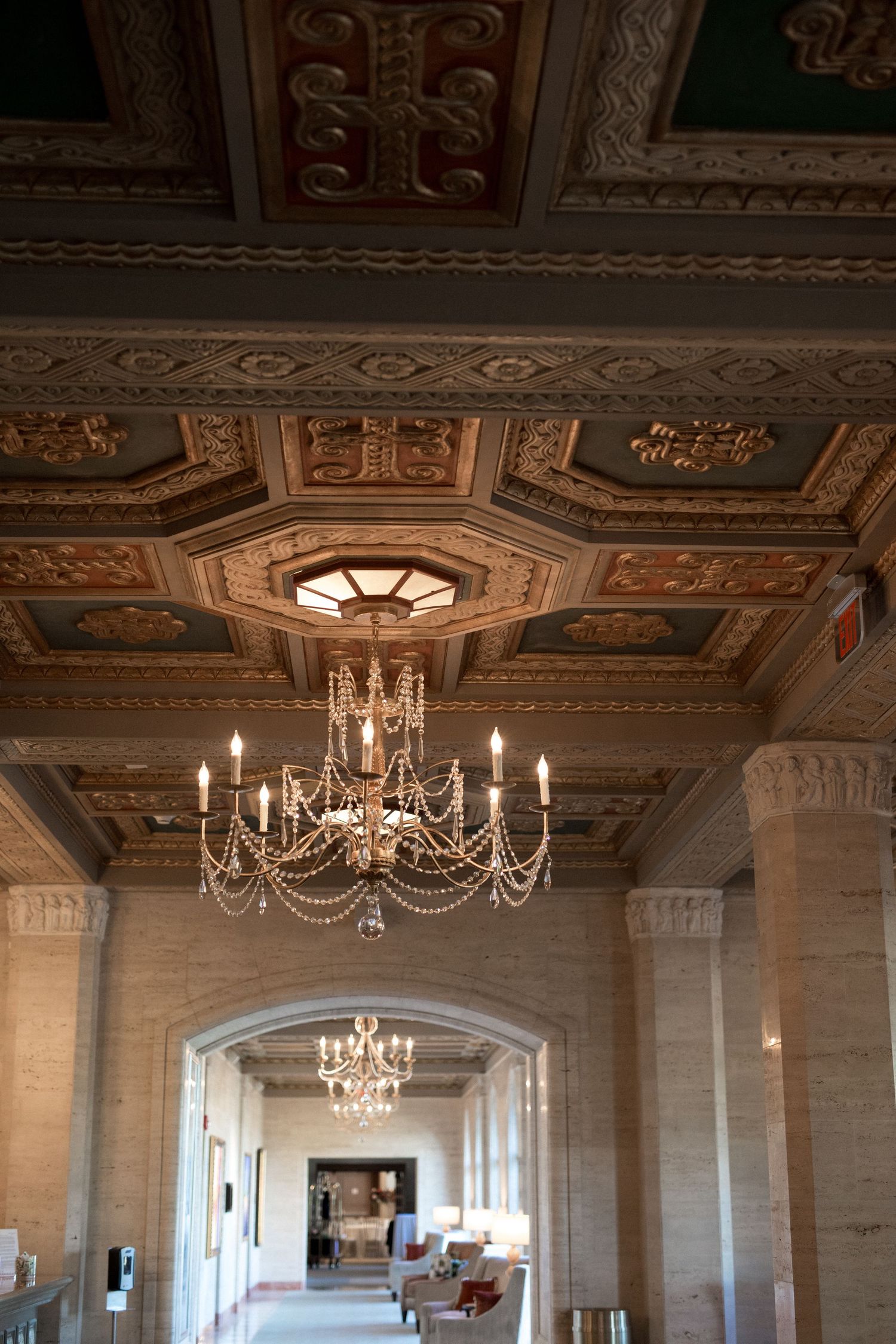 Elegant ballroom with ornate ceiling featuring crystal chandeliers and detailed architectural moldings.