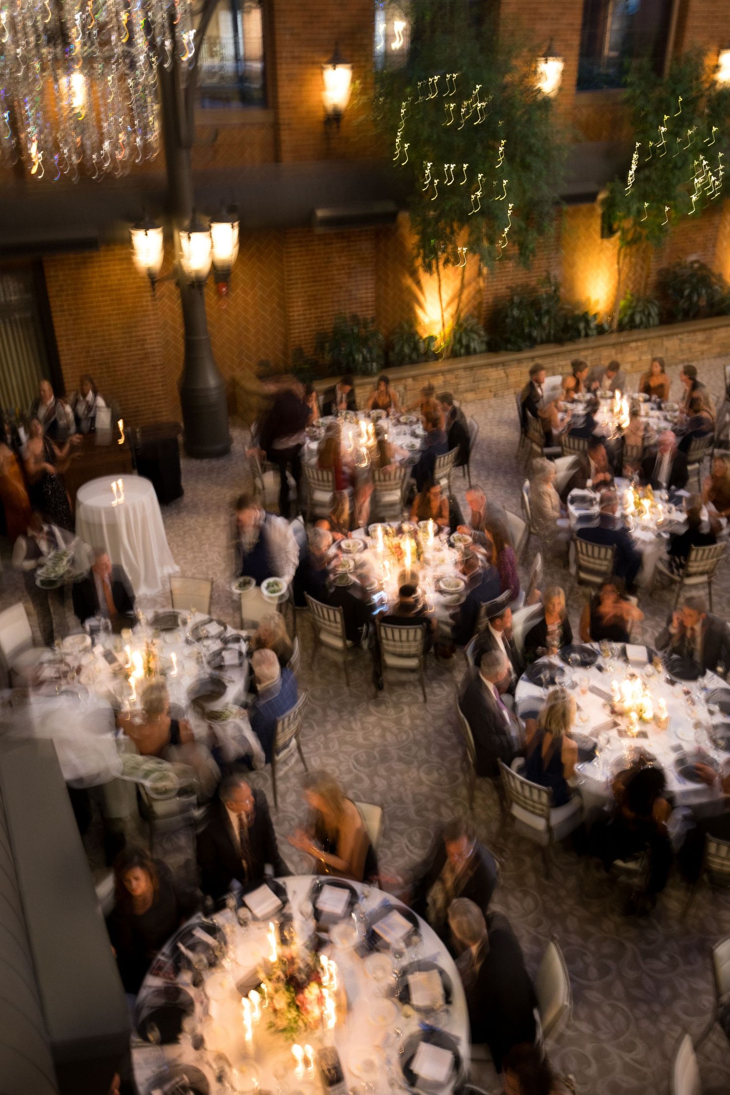 Candlelit wedding reception tables arranged in a grand hall with guests mingling in soft lighting.