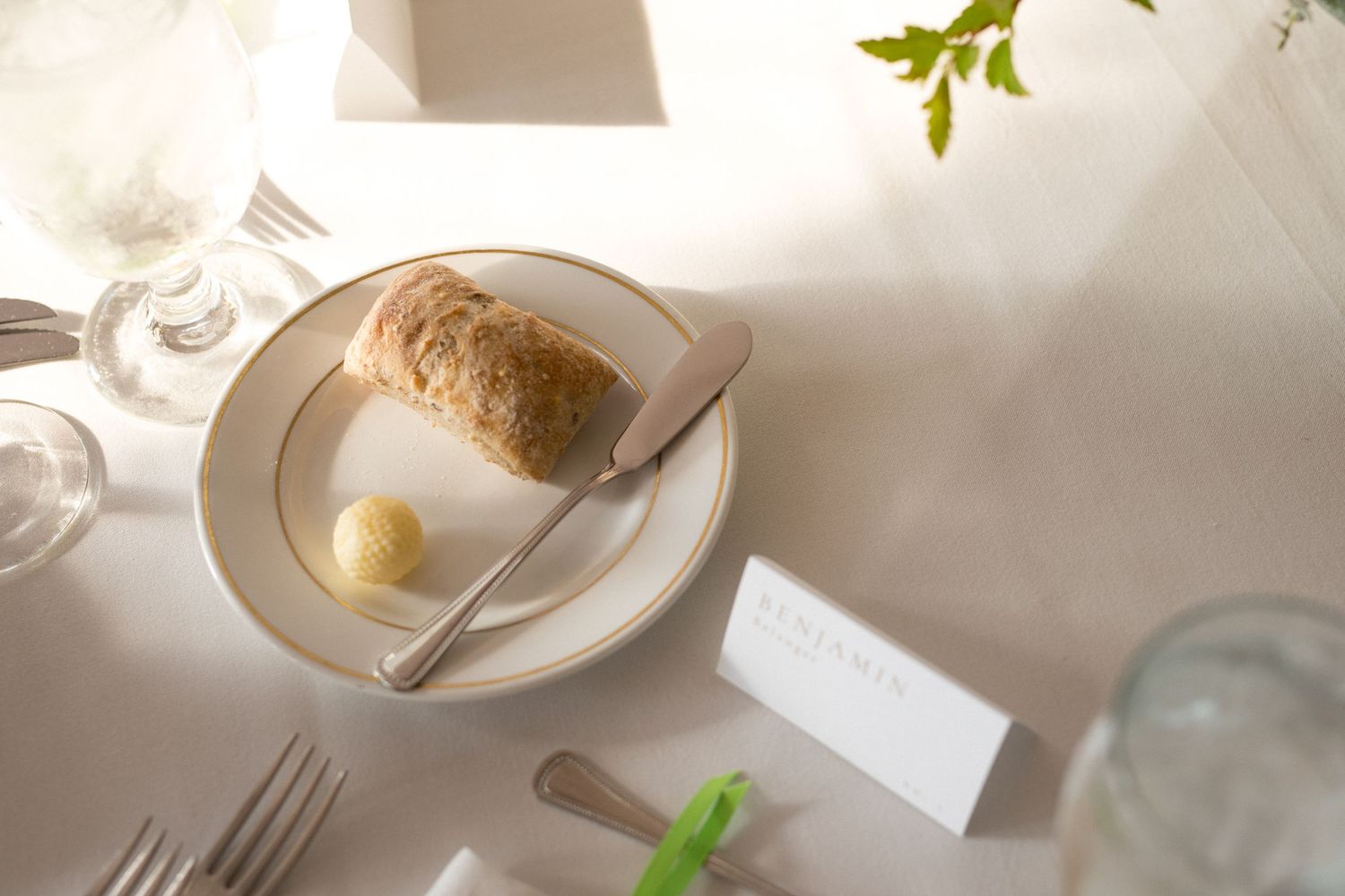 A rustic table setting with white plates, scattered leaves, and natural decor creates an elegant dining atmosphere.