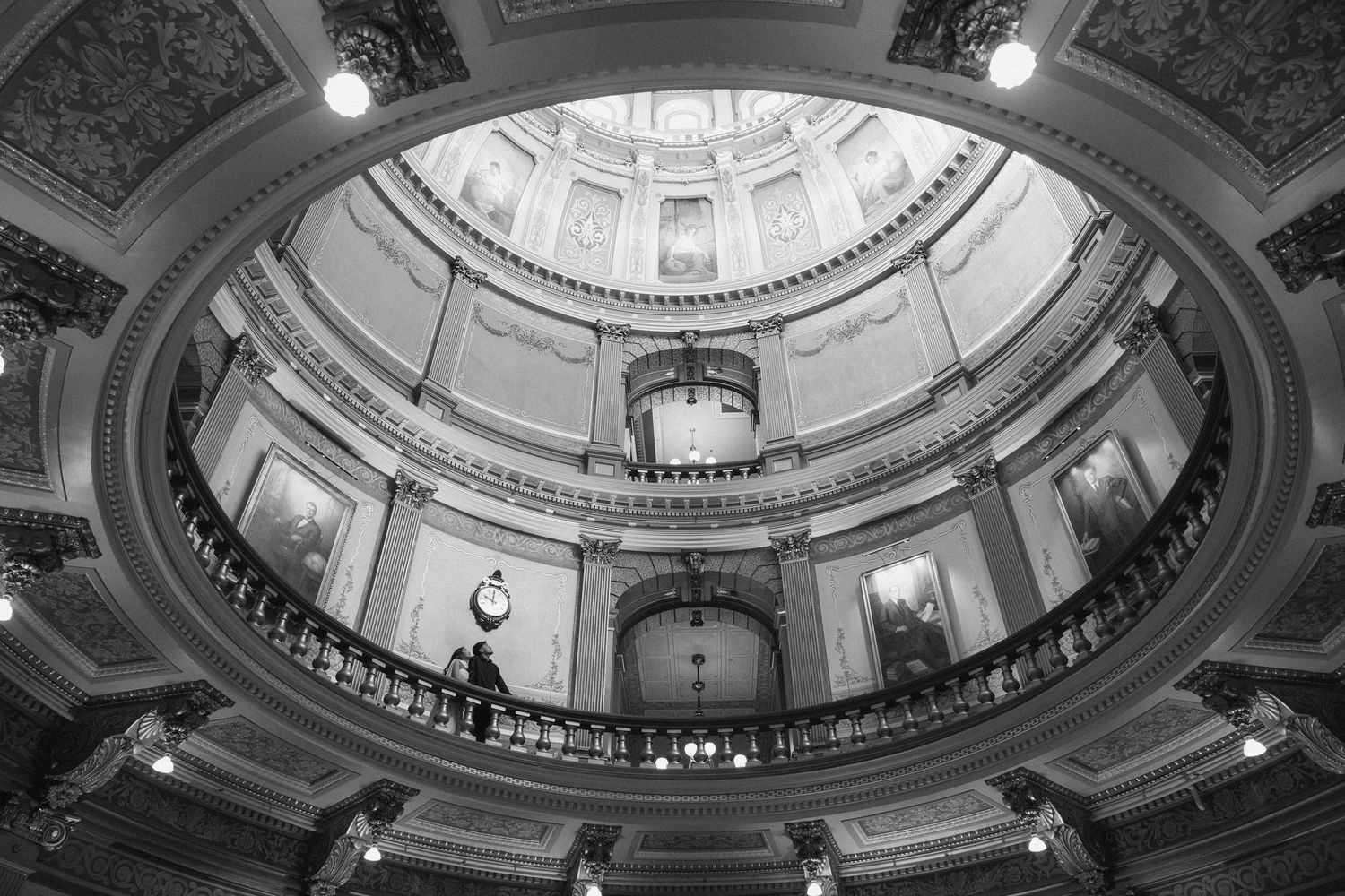 Black and white interior view of a grand capitol building rotunda with ornate balconies and domed ceiling.