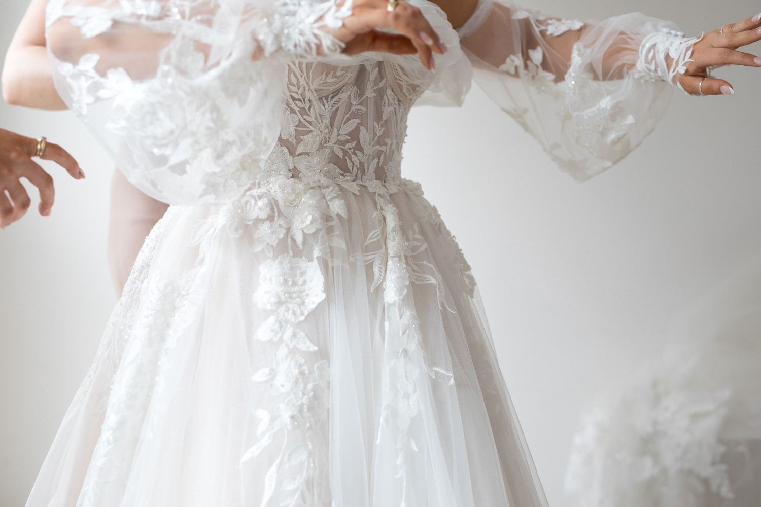 Close-up details of white lace and beaded embellishments on an elegant wedding dress.