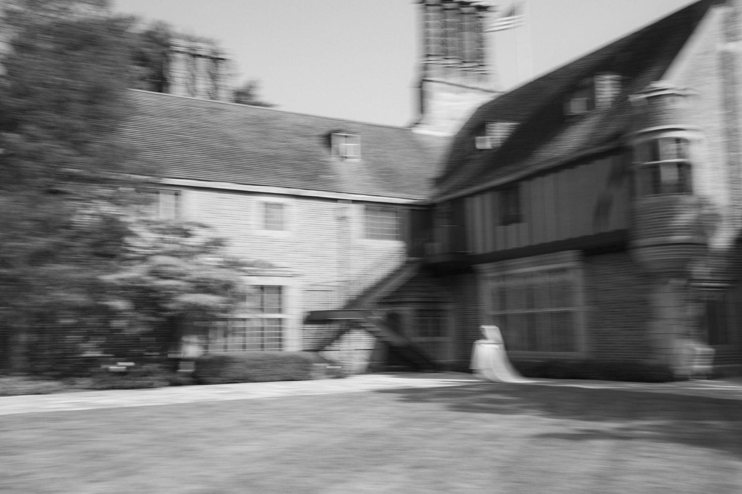 Blurred black and white exterior view of a Tudor-style mansion with architectural details.