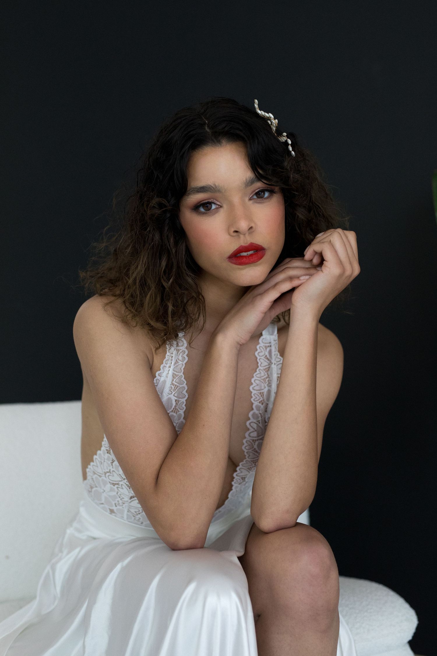 A model in a white lace dress poses against a dark background in a series of glamour shots.