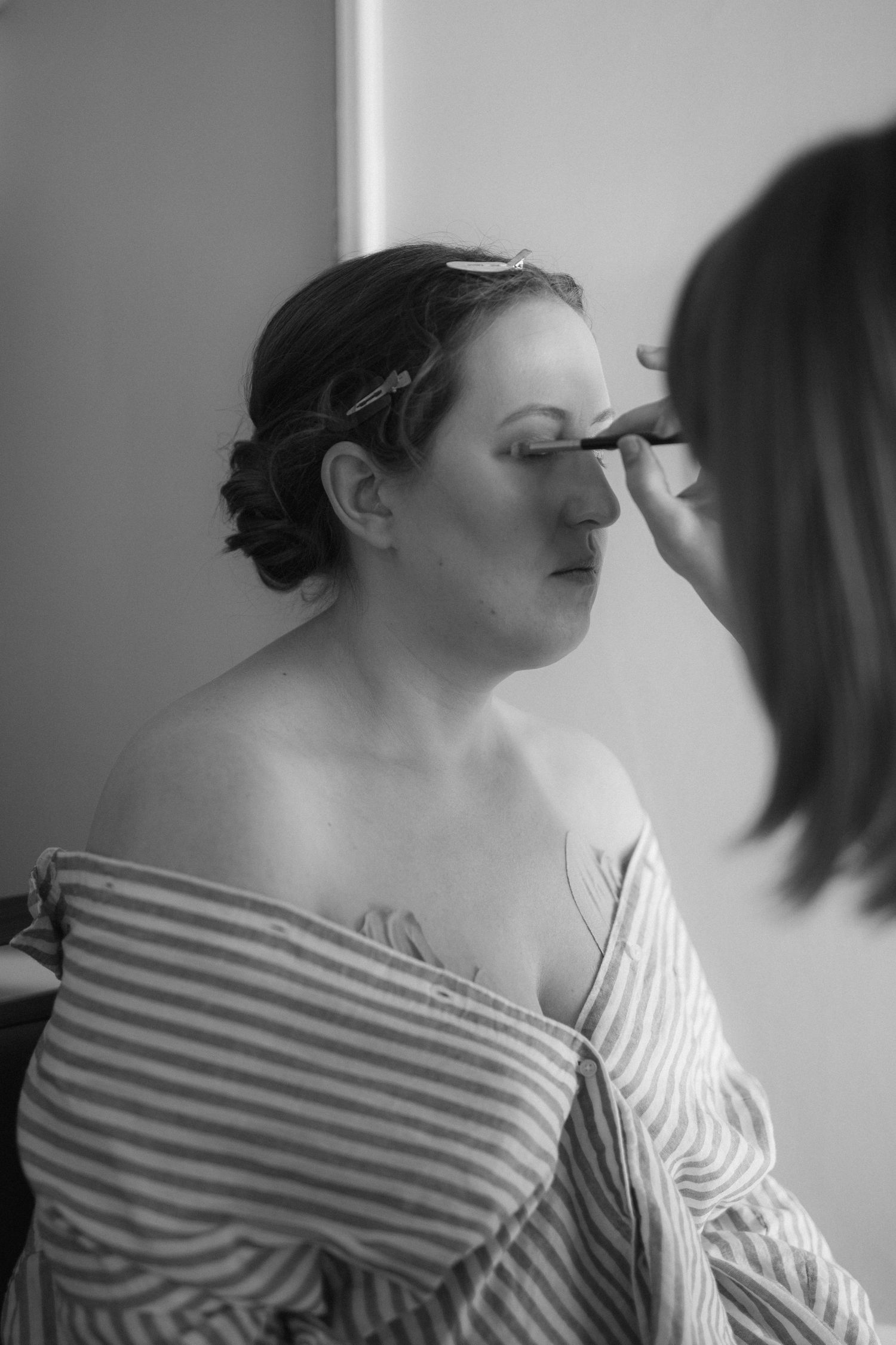 A sequence of black and white portraits showing a person in a striped off-shoulder top looking upward.