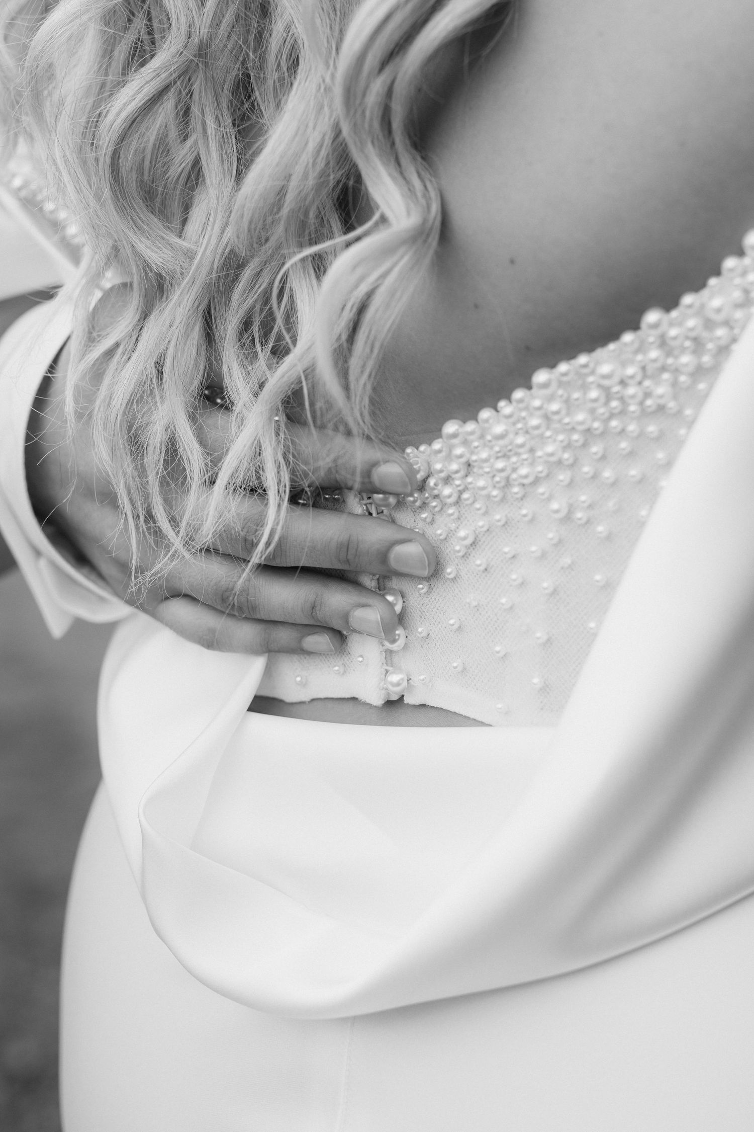 A close-up series of a bride's delicate pearl necklace being fastened around her neck in a wedding preparation moment.