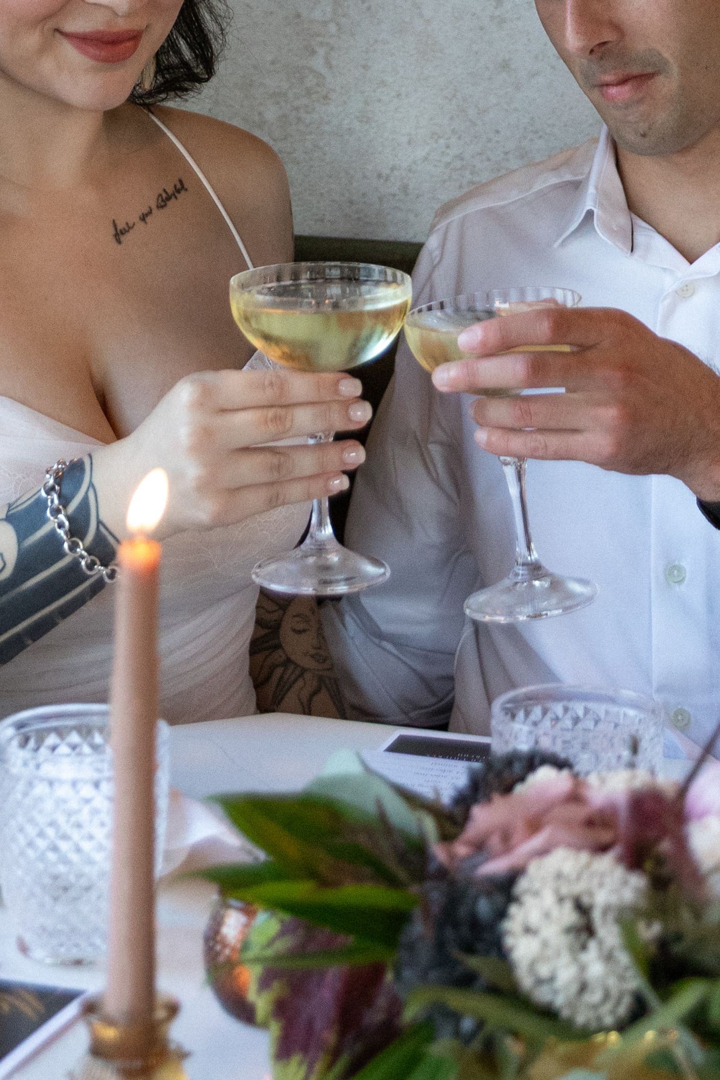 People enjoying cocktails and conversation at an elegant dinner table with candlelight and floral arrangements.