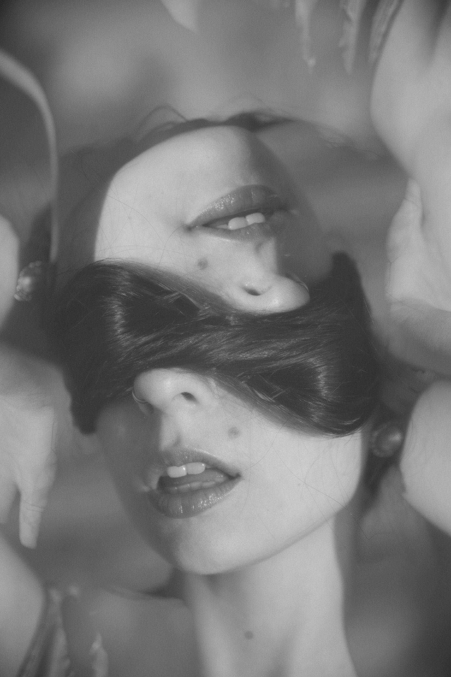 A black and white artistic collage of facial close-ups showing lips and partial features in a dreamy style.