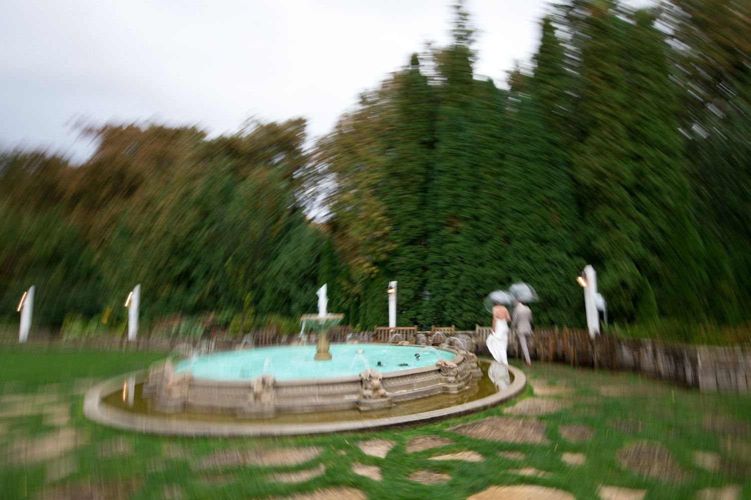 A panoramic view of a mini golf course with white flag markers and green artificial turf surrounded by trees.