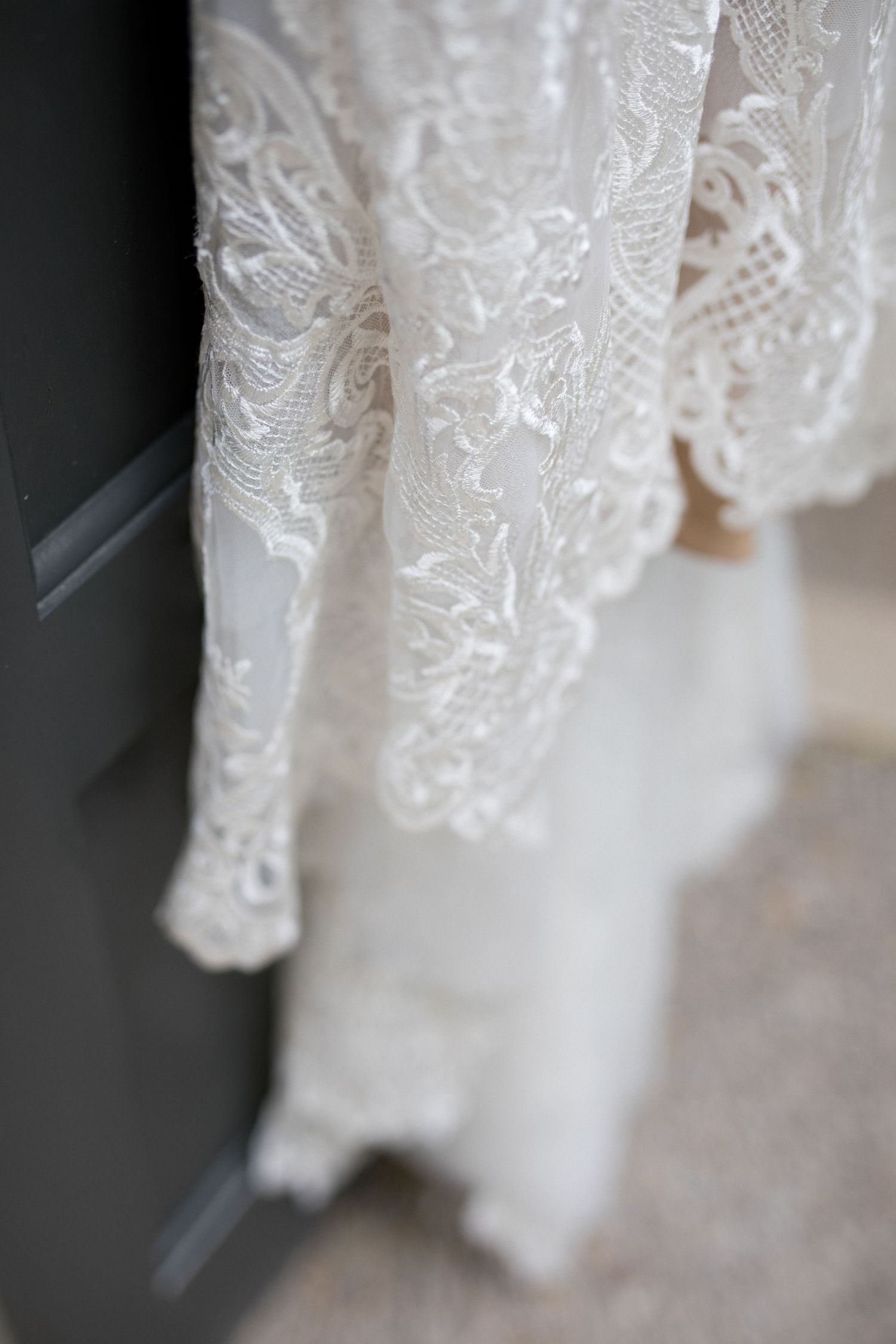 Delicate white lace detail on a wedding dress shows intricate floral patterns and embroidery work.