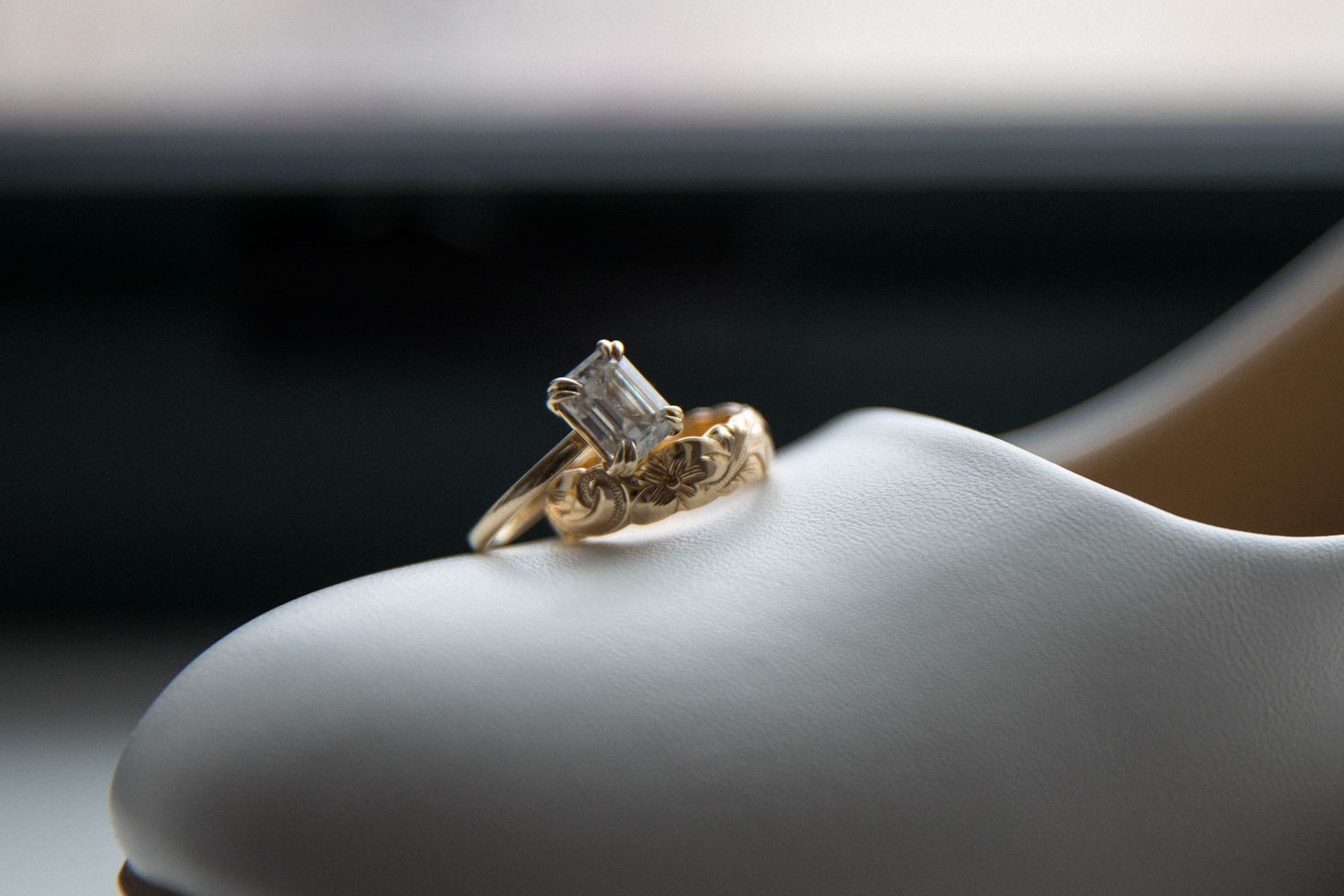 Close-up detail of a white bridal shoe against a blurred background.