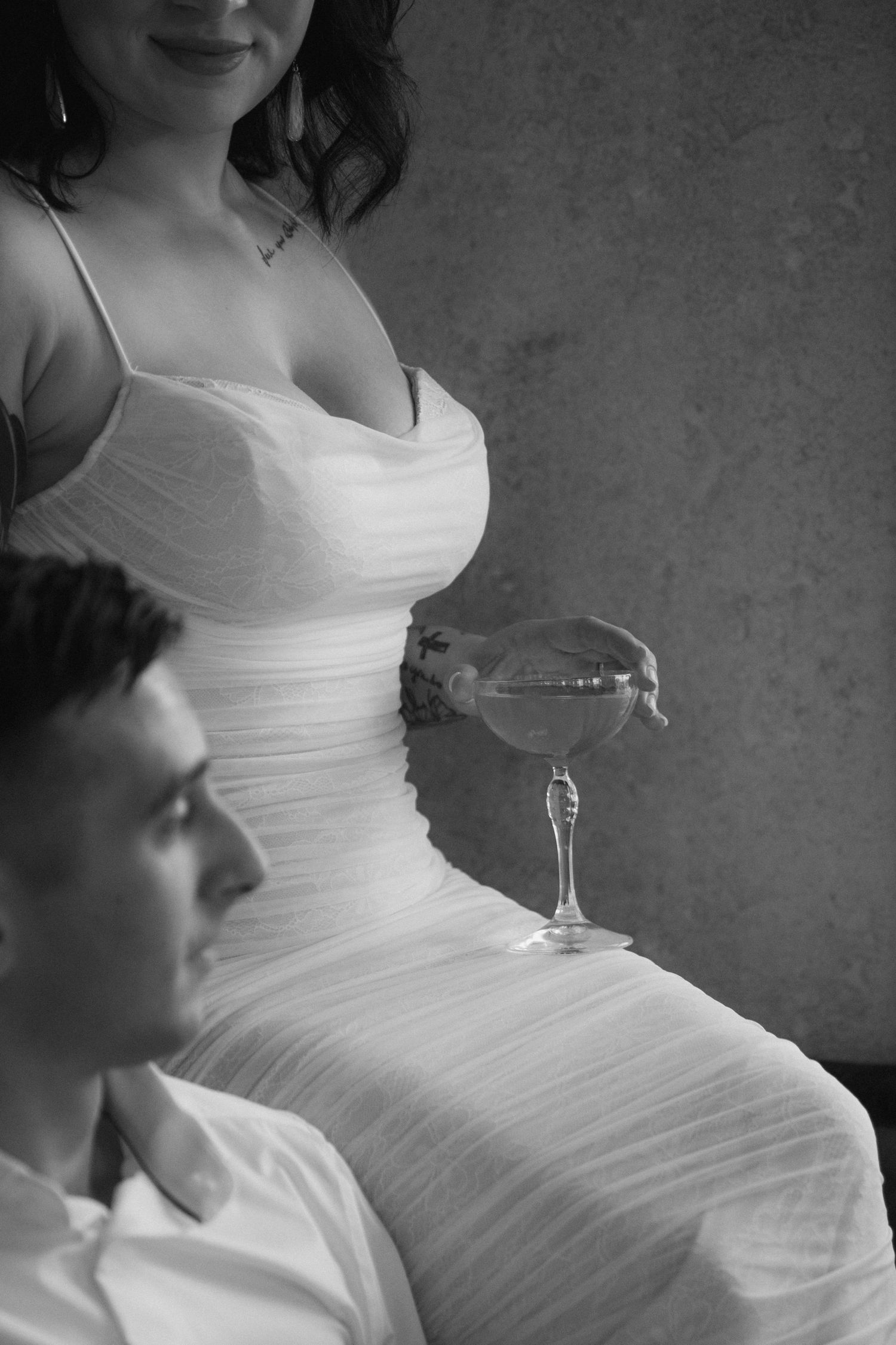 A series of black and white photos showing someone in a white wedding dress holding a wine glass.