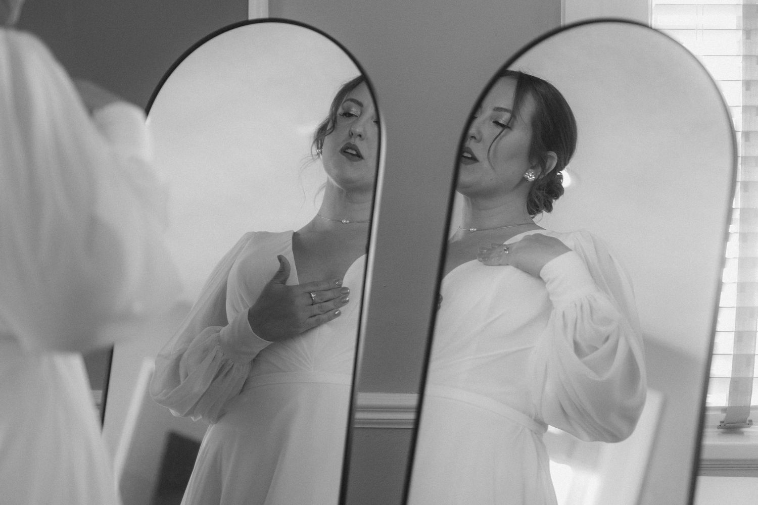 Black and white photo sequence showing someone looking at their reflection and applying makeup in a bathroom mirror.