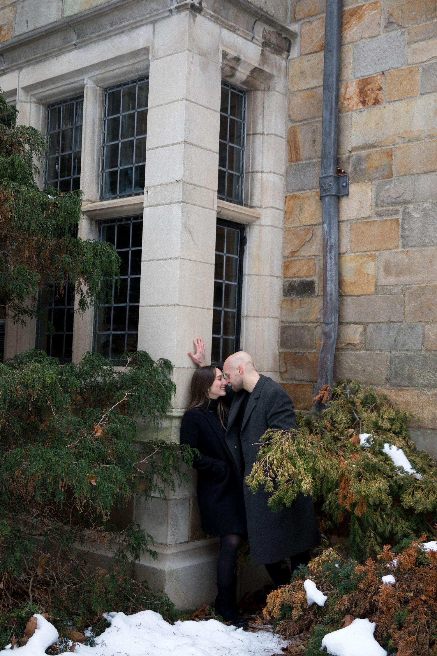 A sequence of four photos showing someone hiding behind bushes and peeking out near a stone building's window.