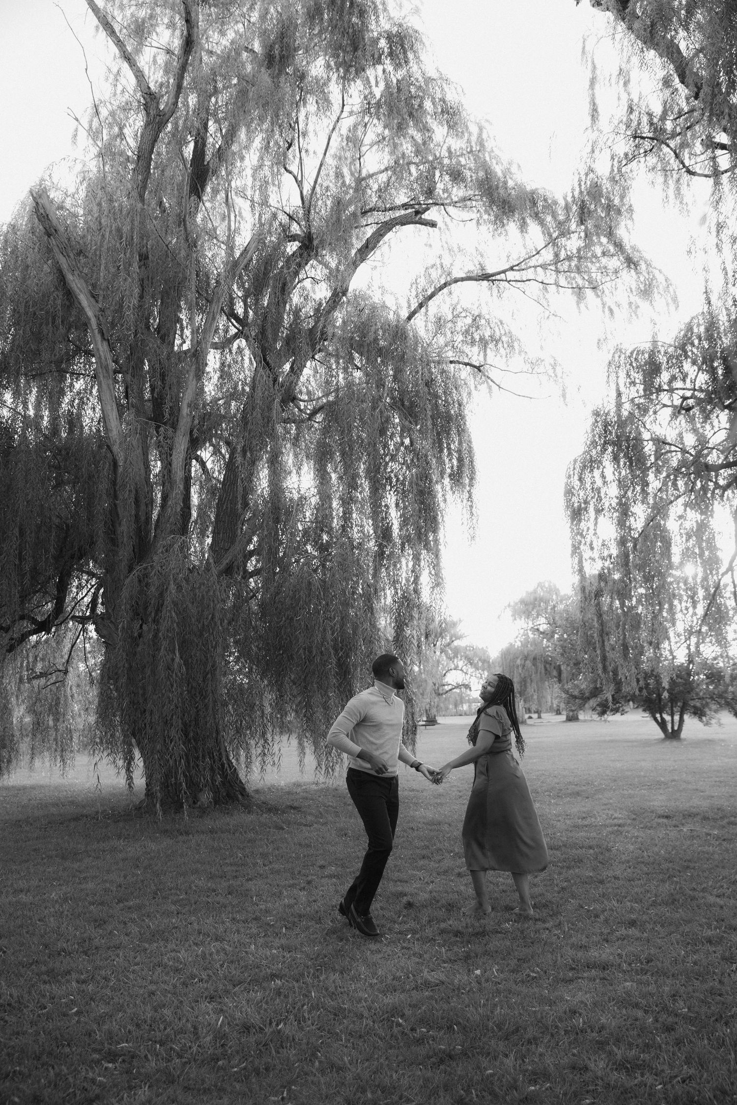 A series of black and white photos showing people dancing together under weeping willow trees in a park setting.