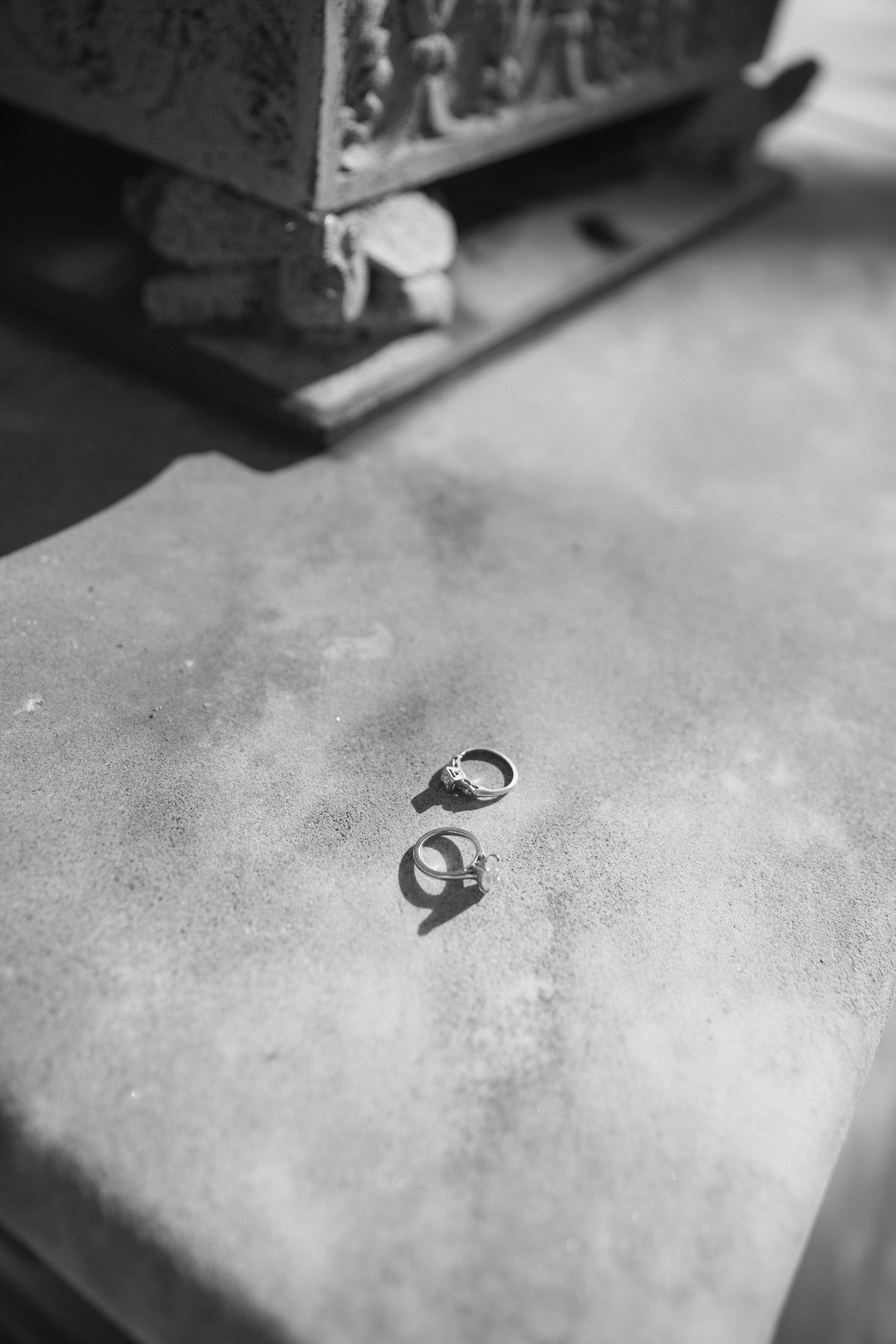 Black and white photo of two wedding rings casting shadows on a stone surface.