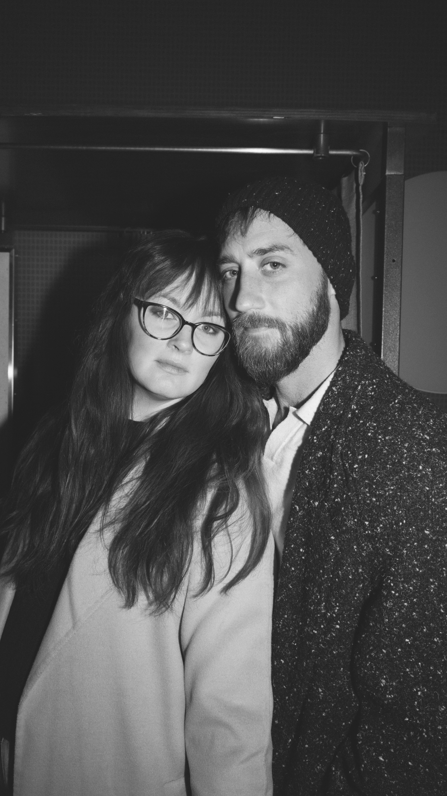 Black and white photo series showing a couple in close embrace with one person wearing glasses and a sparkly jacket.