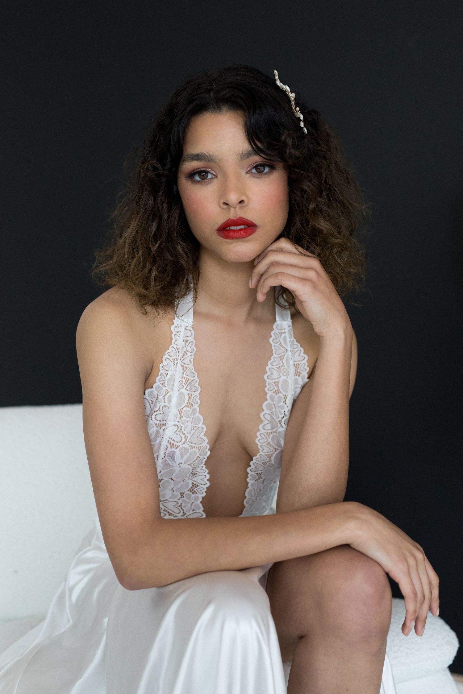 A white lace lingerie set is showcased against a dark background in a glamour photography series.