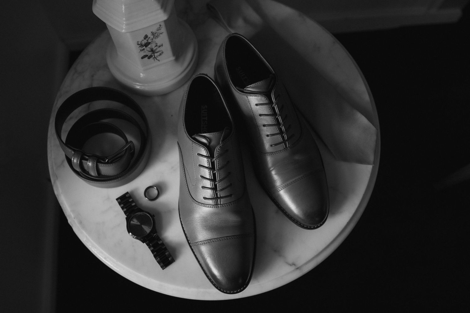 Black leather dress shoes displayed in various angles on white plates against a dark background.