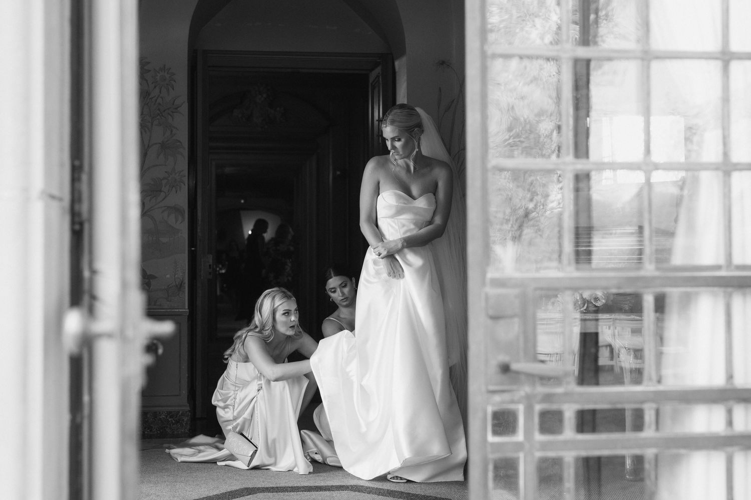 Black and white photo of a bright interior space with large windows and people in formal attire.