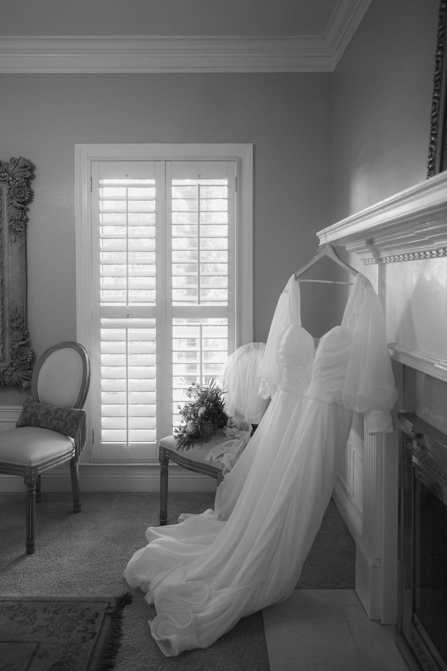 A series of black and white photos showing wedding dresses hanging in elegant rooms with white shuttered windows.
