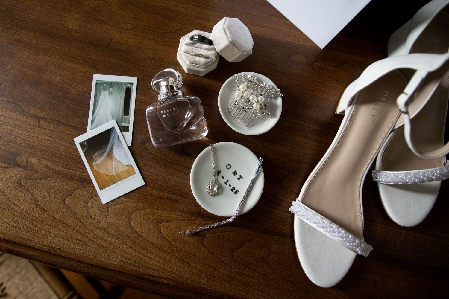 White wedding shoes and accessories arranged on dark wooden floor create an elegant bridal styling flatlay.