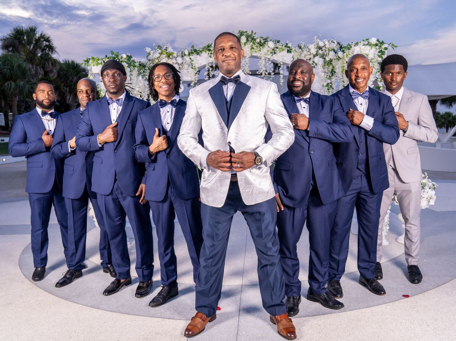 Groom and Groom's men in blue suits posing under a flower lined archway at Tuckahoe Mansion Estate.