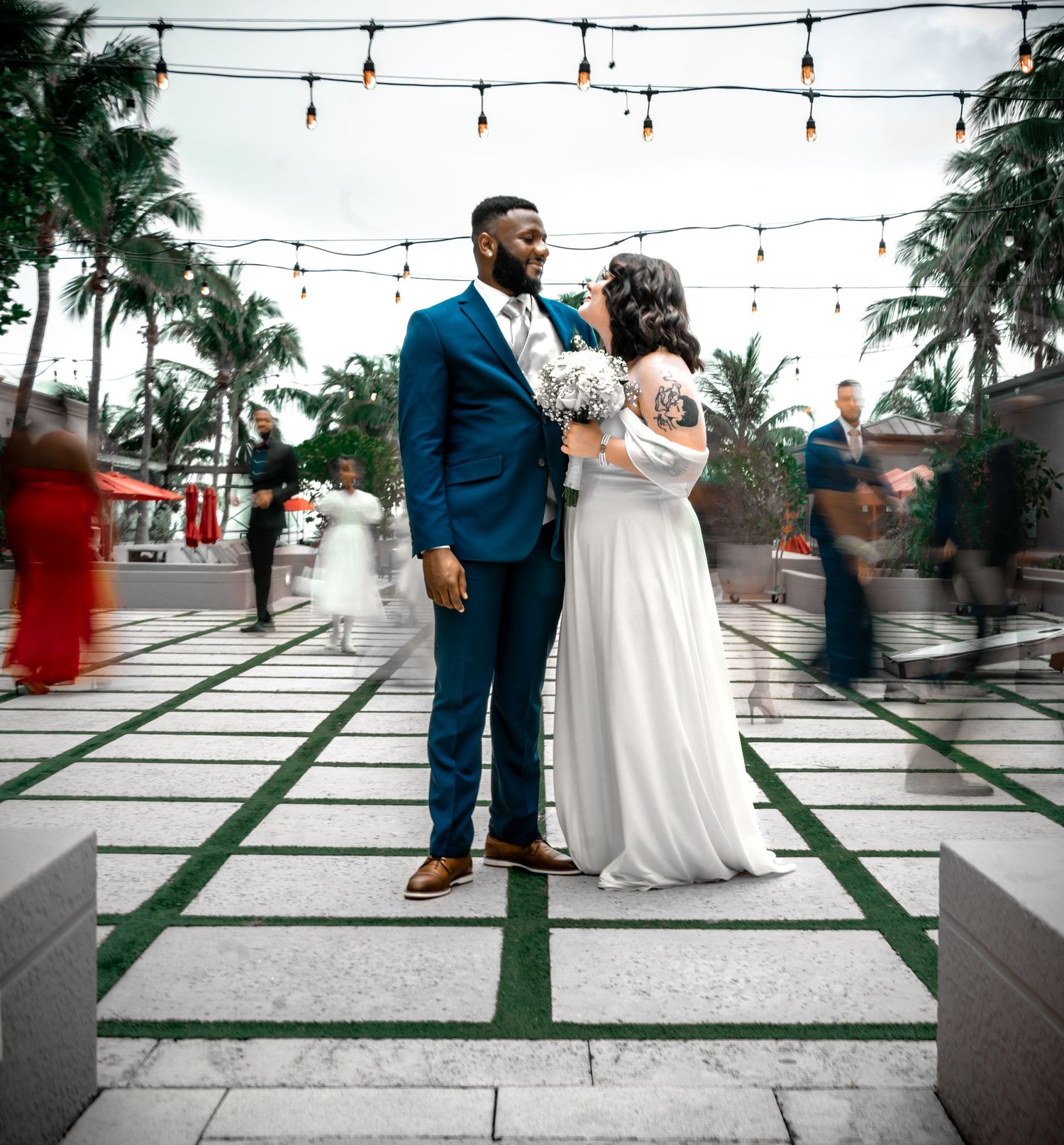 bride and groom looking into each other's eyes on patio as couples around them are blurred.