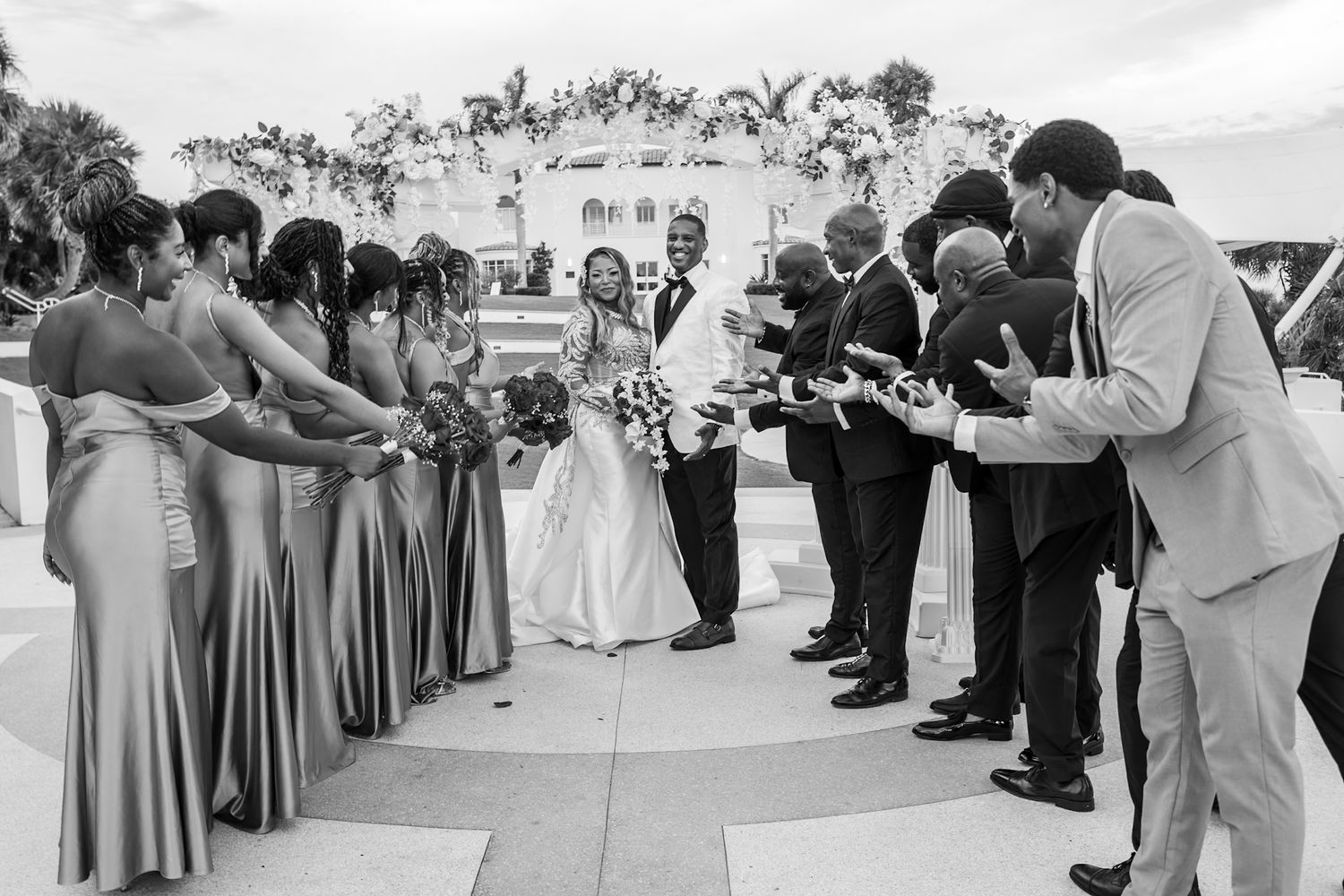 Black and white photo of black couple posing at the center of the photo and bridal party all pointing towards them at tuckahoe mansion.