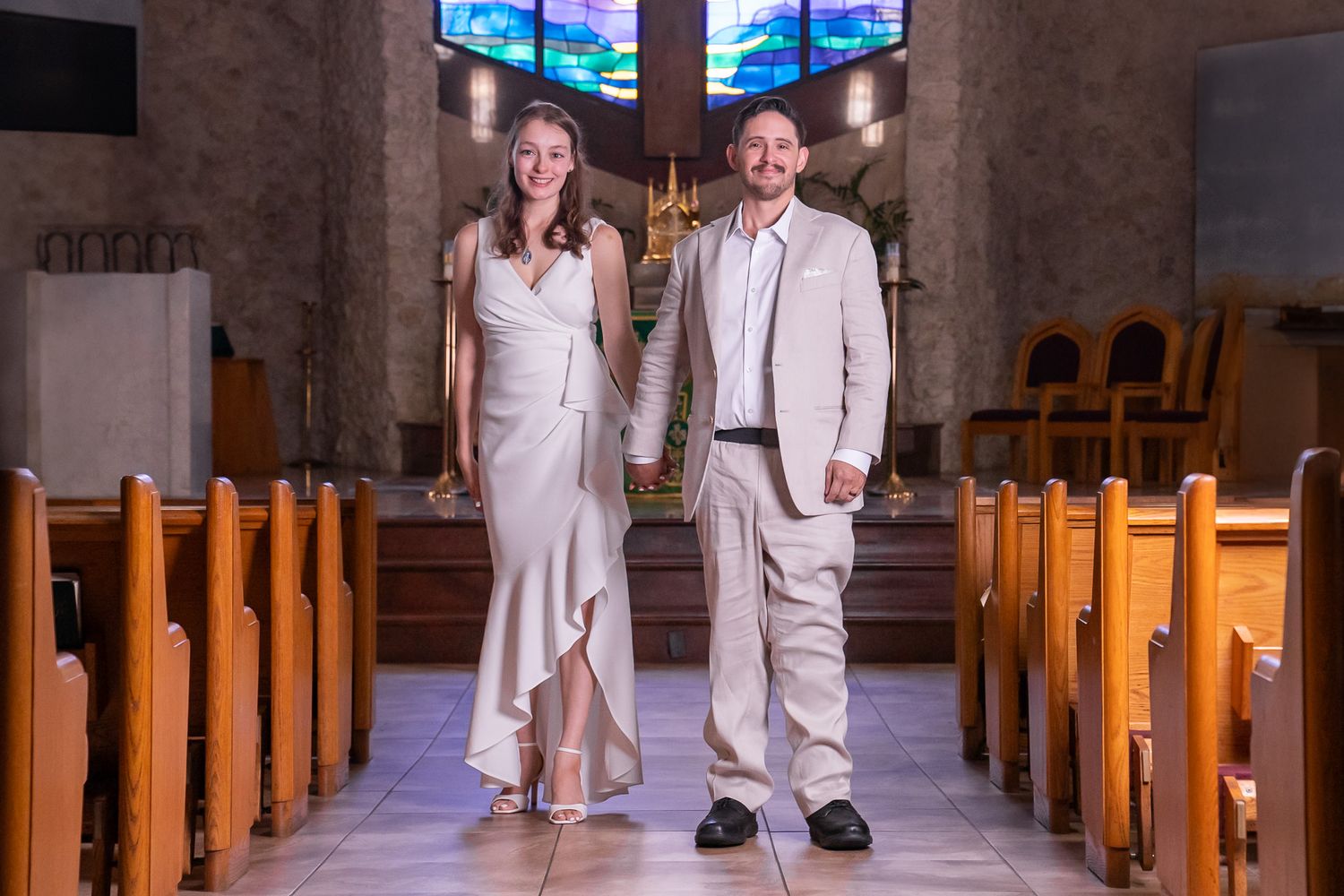 Bride and groom hold hands in church as they walk down the isle after marriage ceremony.