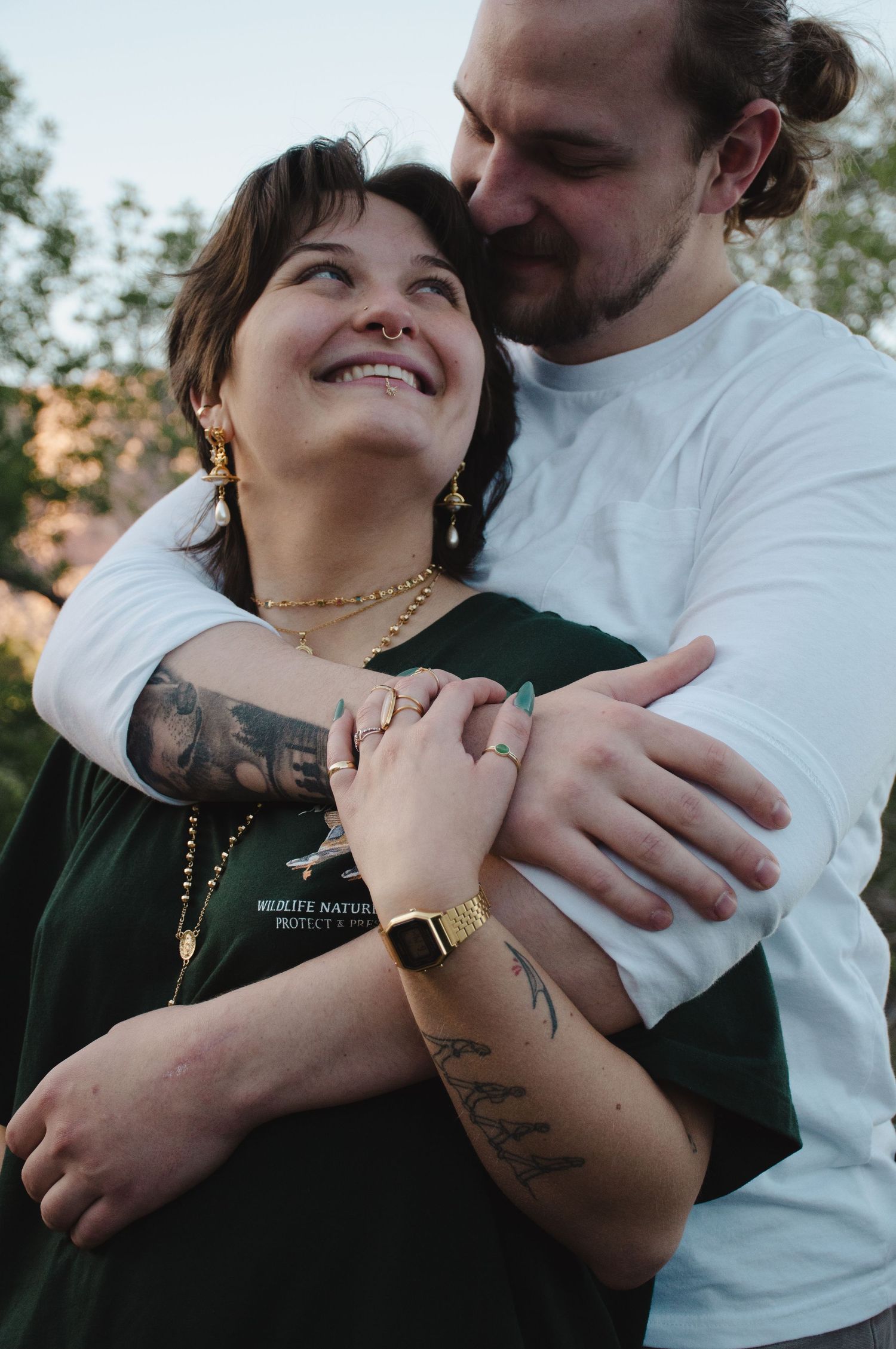 woman nestled close into her man's arms smiling and looking at eachother