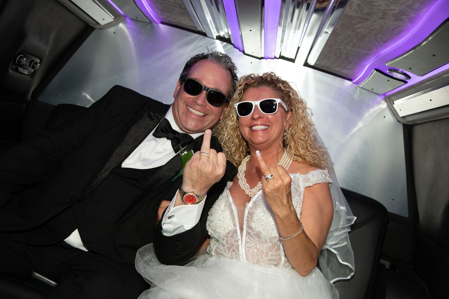 Couple showing off wedding rings in limo