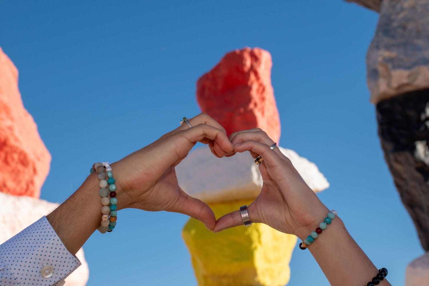 Couple making a heart in front of the seven magic mountains