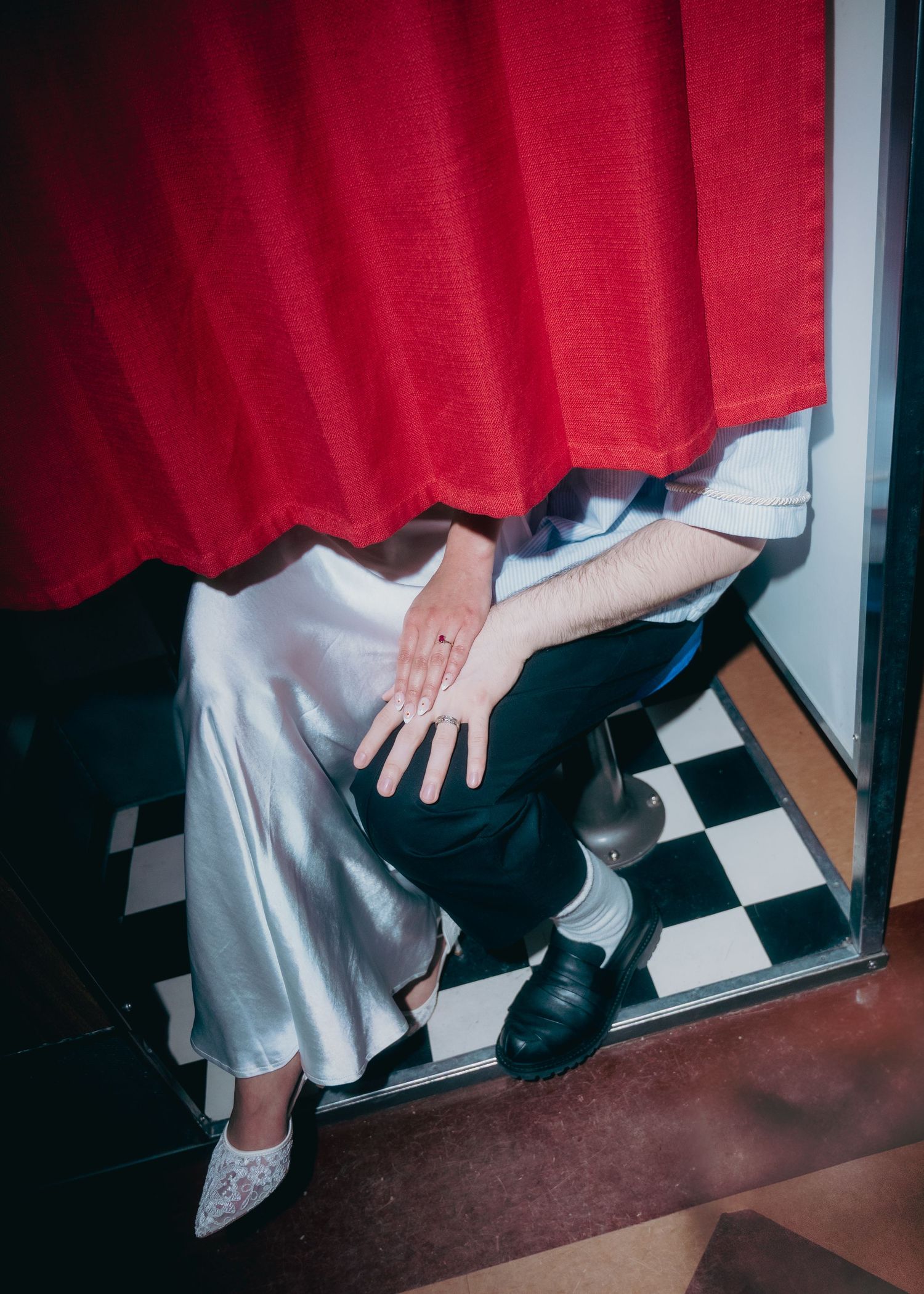 Engaged couple showing off rings in a vintage style photo booth
