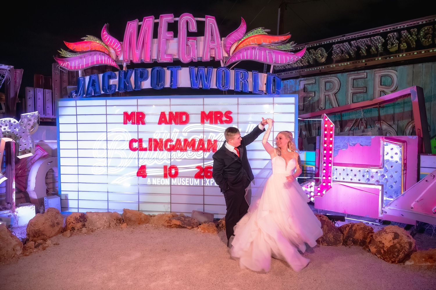 Bride and groom dancing at the neon museum with a marquee sign with their wedding date