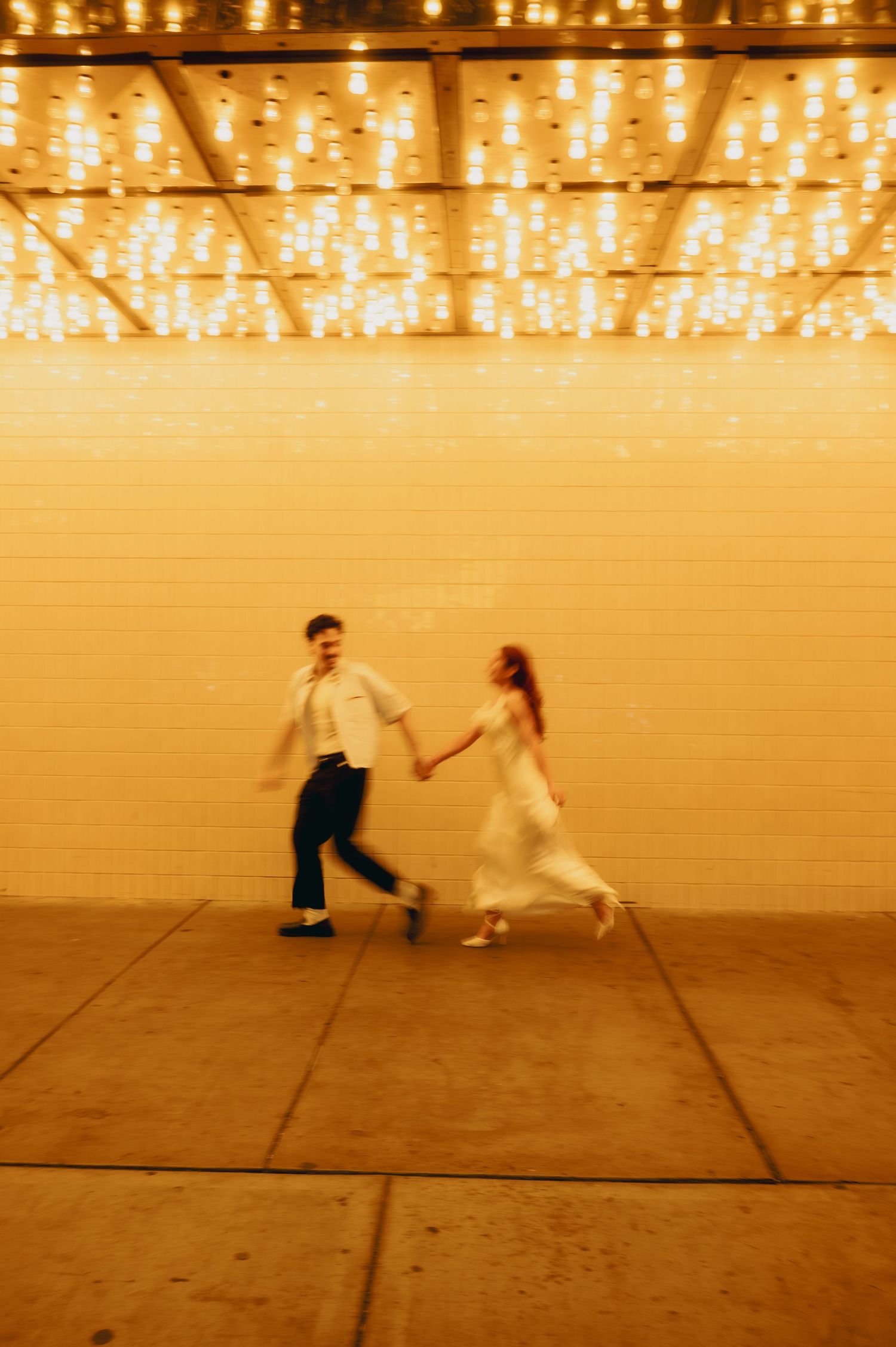 engaged couple running underneath the neon lights of Fremont street. Las Vegas Engagement session inspiration