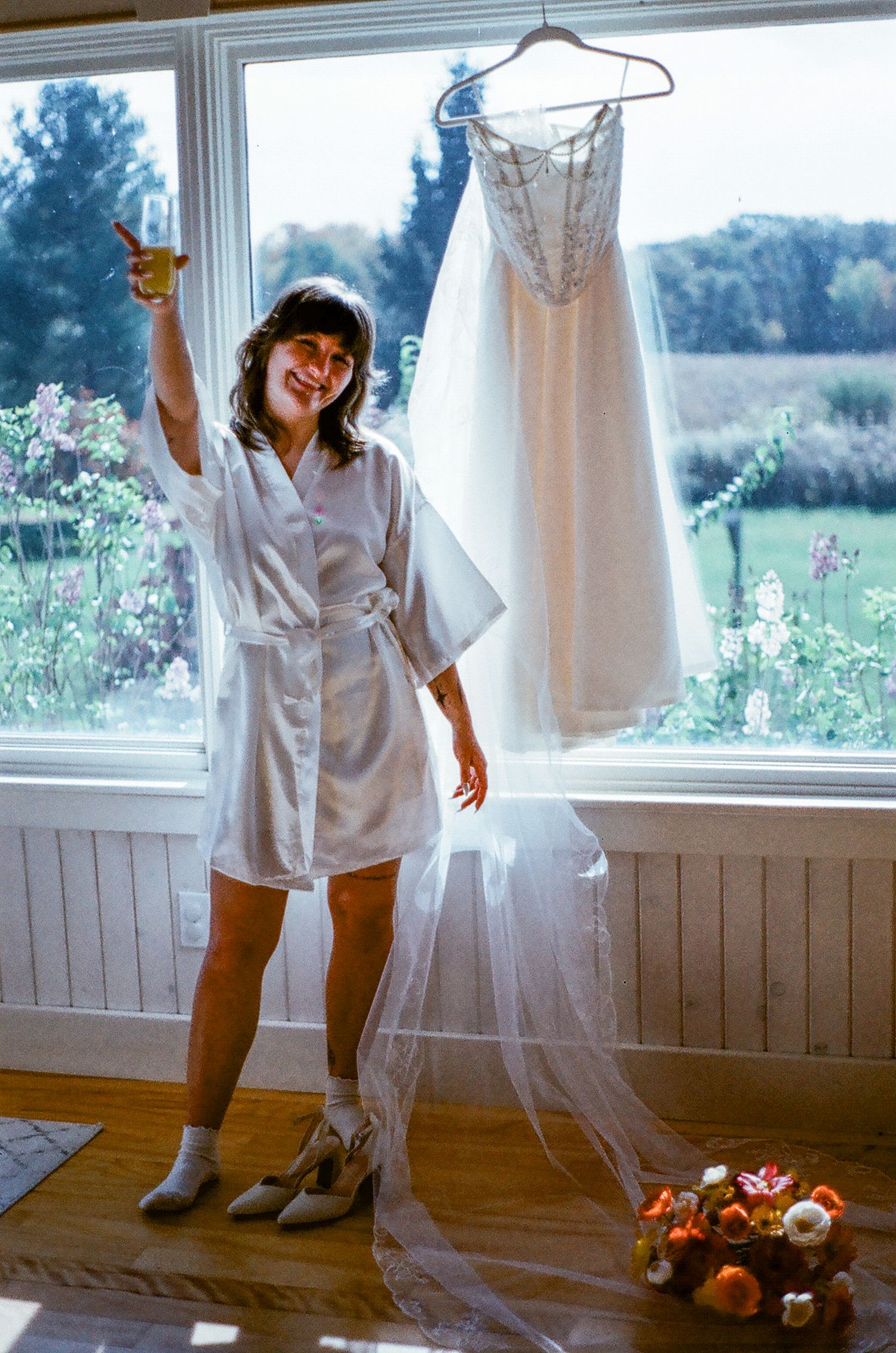 Bride standing next to her dress drinking a mimosa