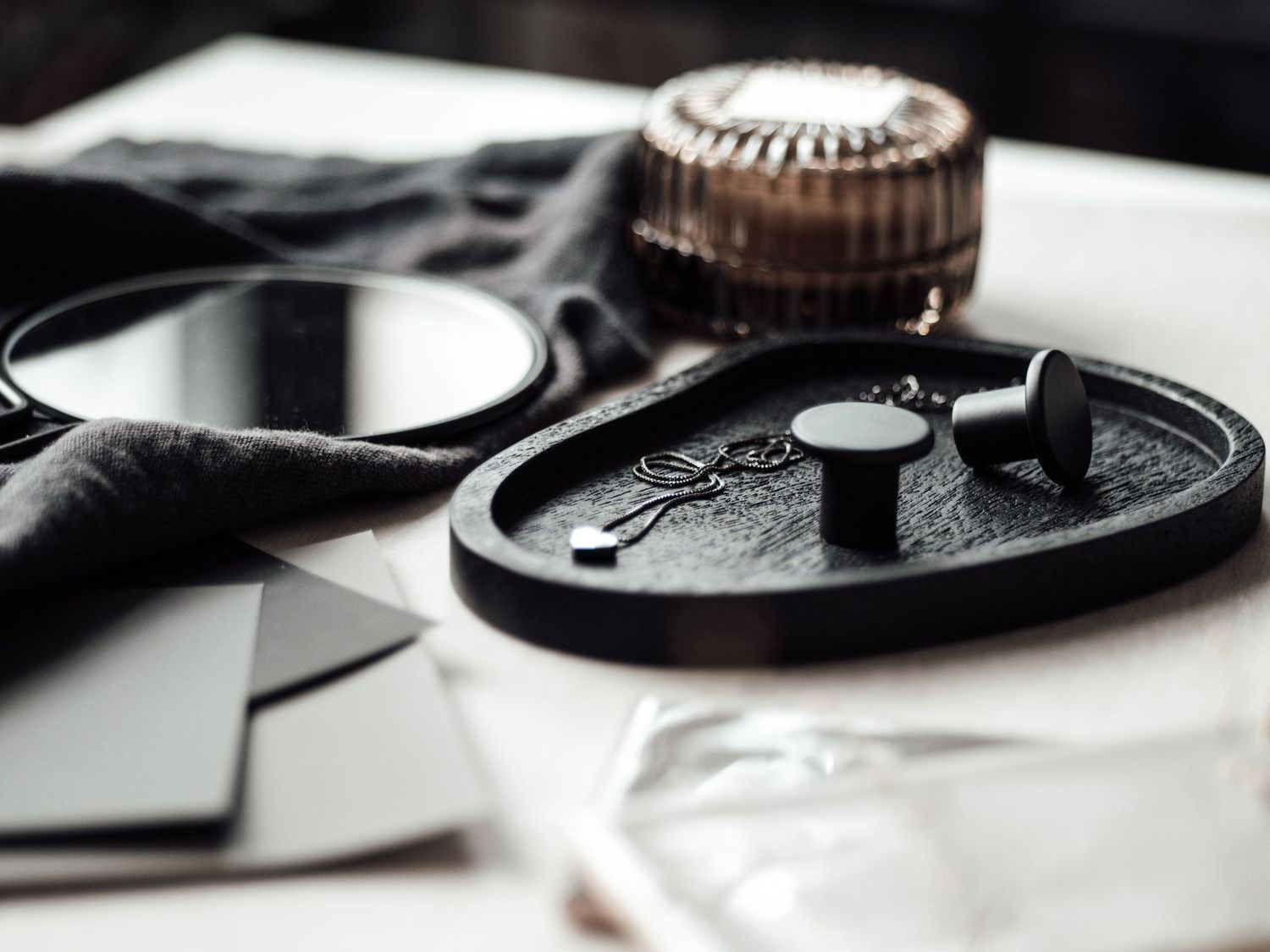Elegant black tray with mirror, key detail, and accessories arranged on a marble surface.