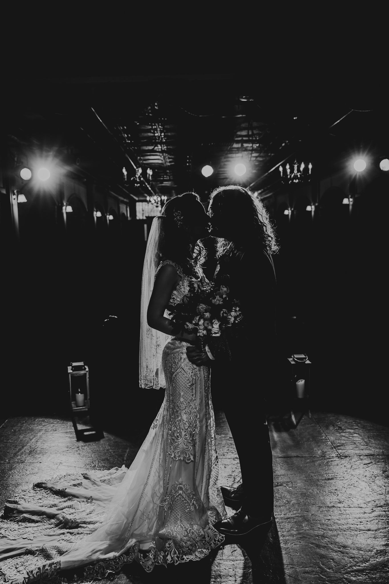 Elegant couple dancing in a dark ballroom with dramatic black and white lighting and shadows.