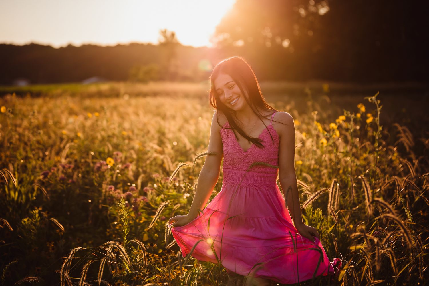 Figure in pink dress twirling in golden sunlit field at sunset.