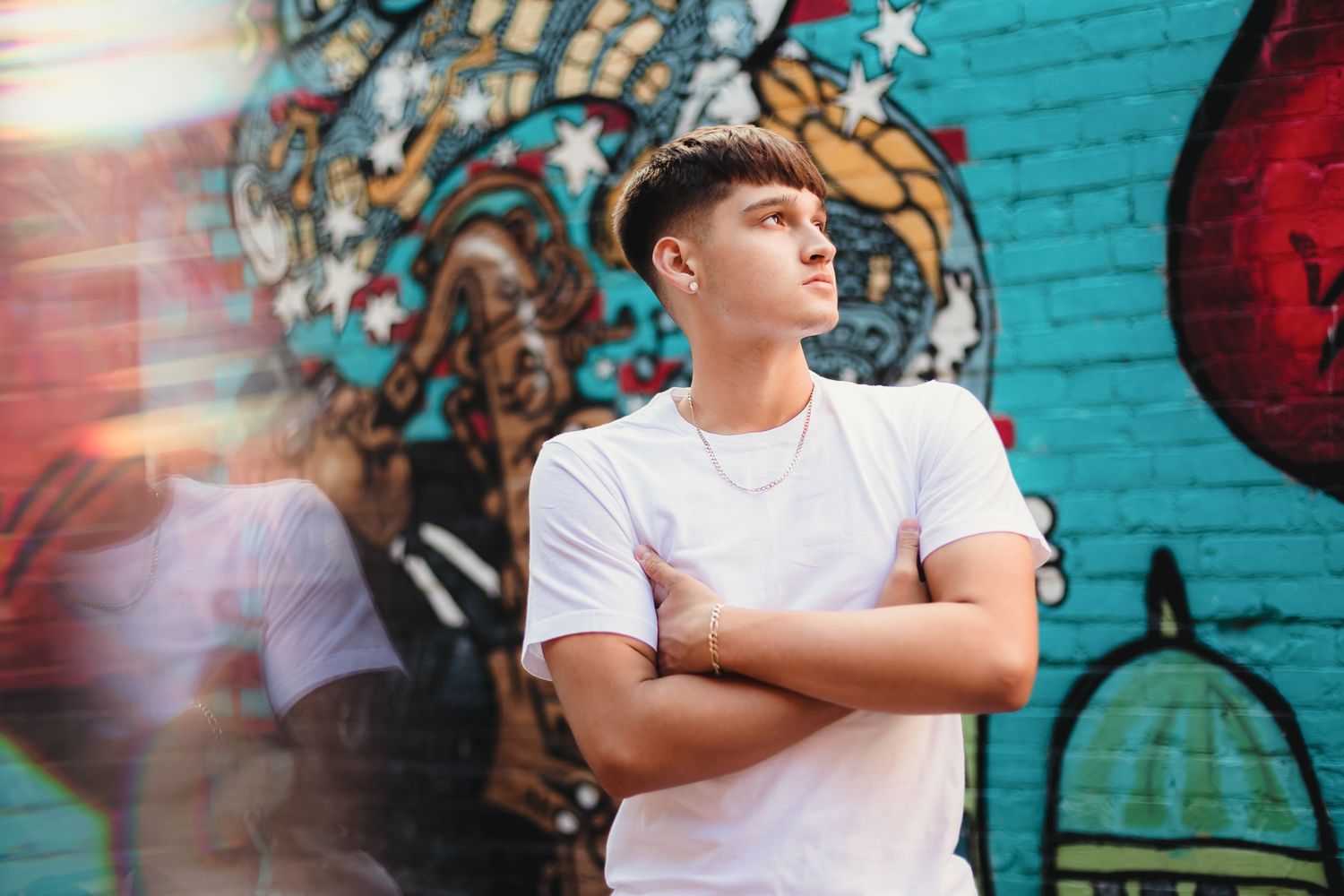 Urban portrait against colorful graffiti wall with sun flare.
