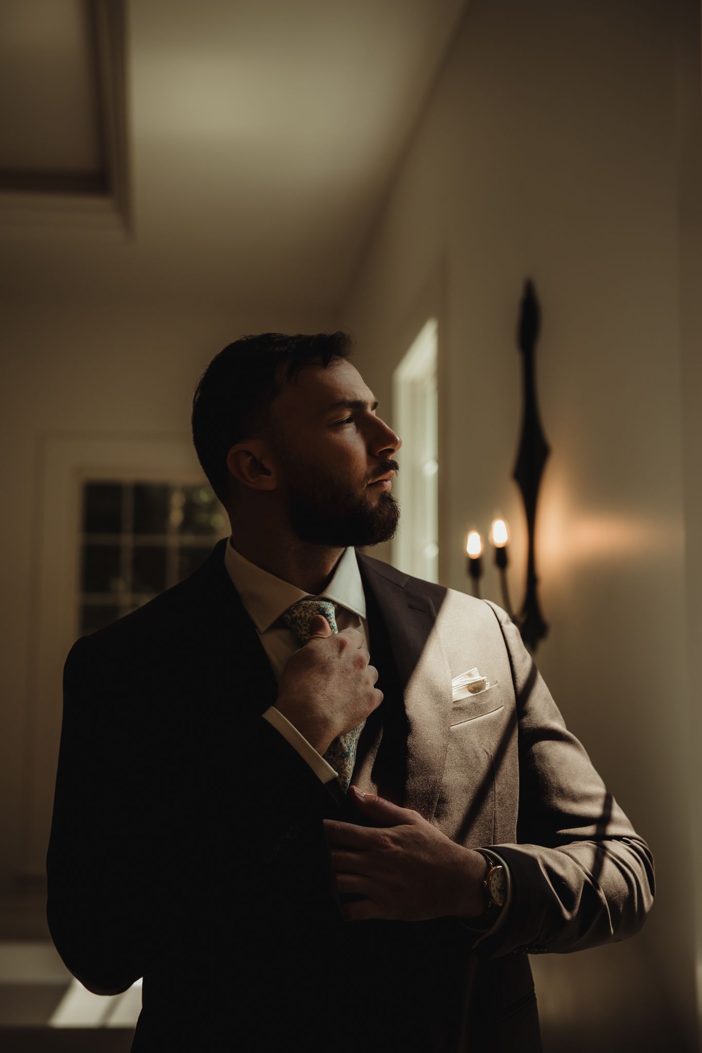Moody portrait in dark room with dramatic side lighting creating atmospheric shadows and contrast.