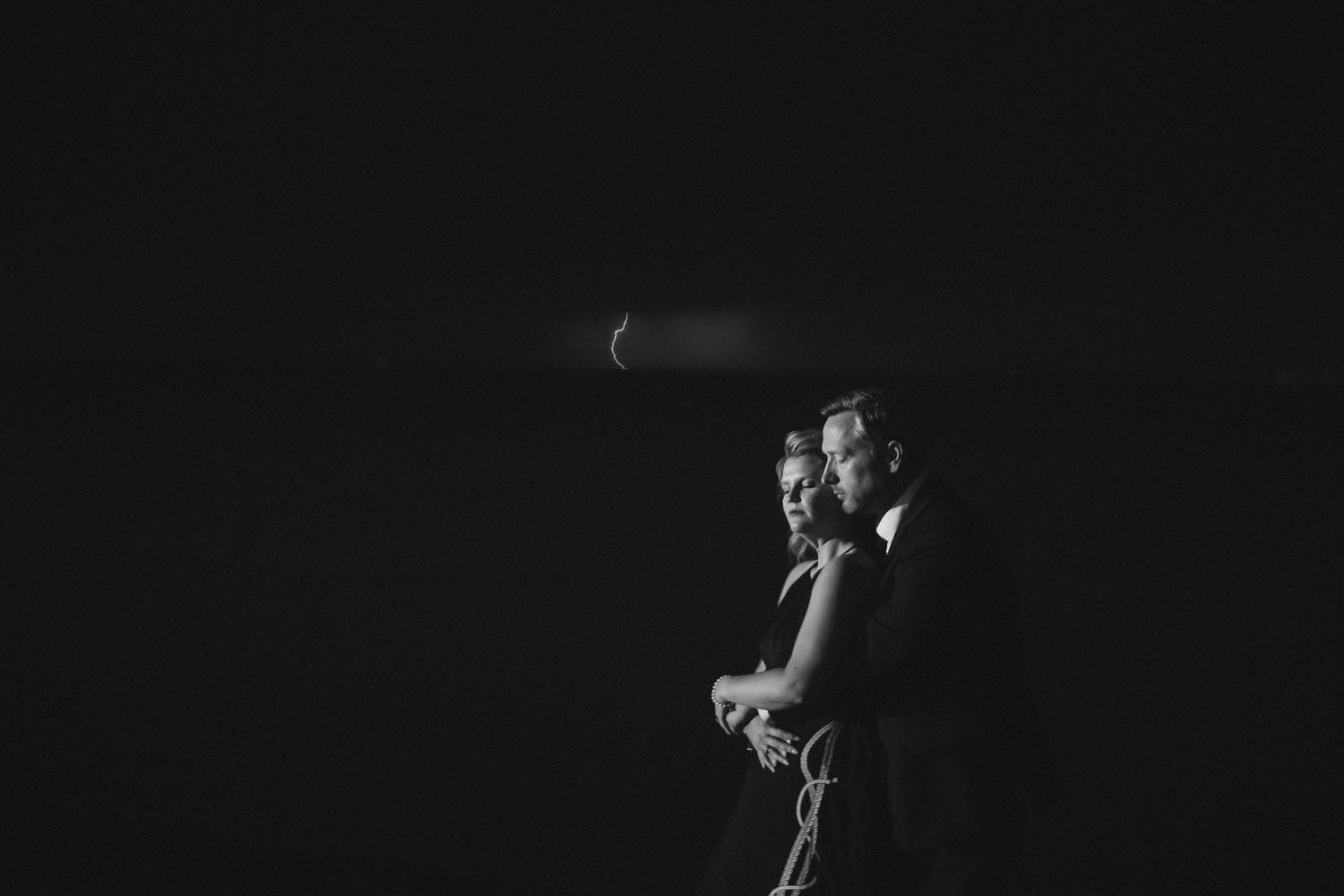 Black and white series of figures silhouetted against night sky holding sparklers.