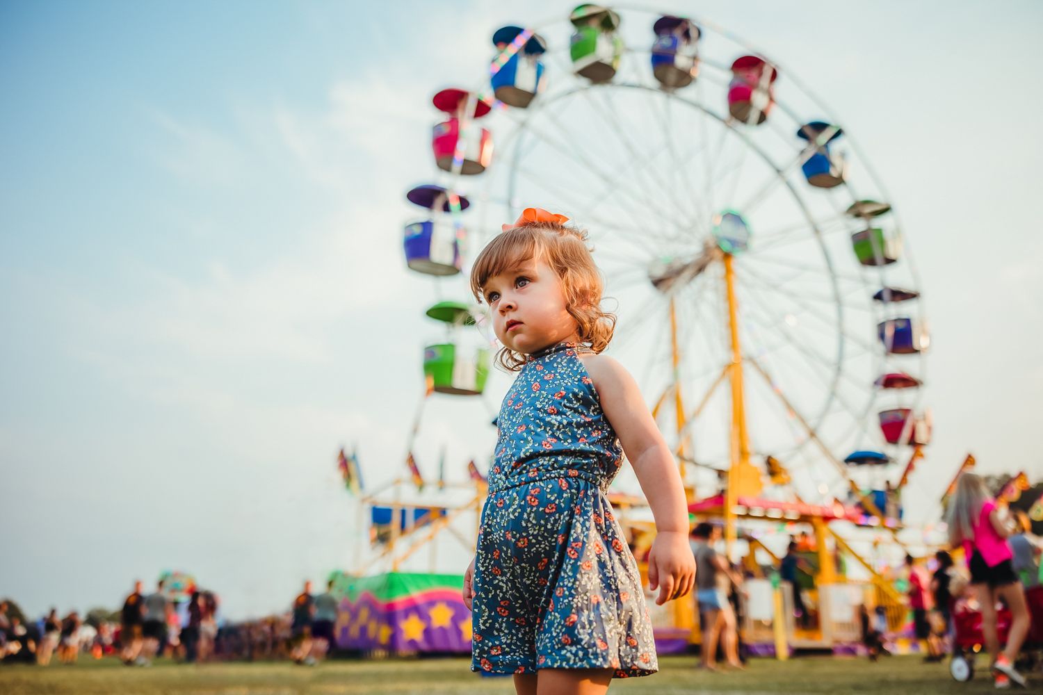 Colorful carnival rides and flags against a bright summer sky.